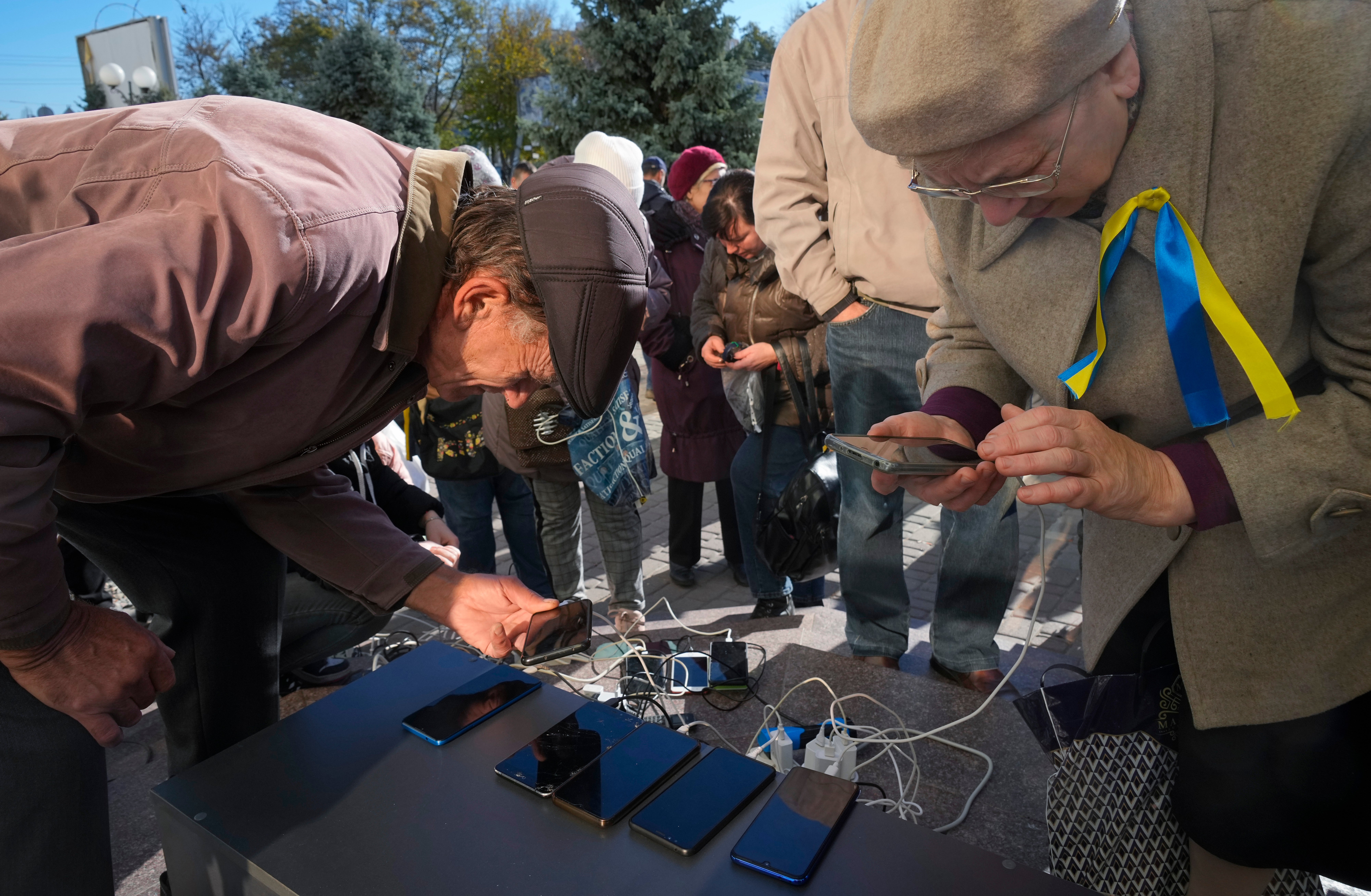 Ukrainians charging phones in Kherson’s central square in November