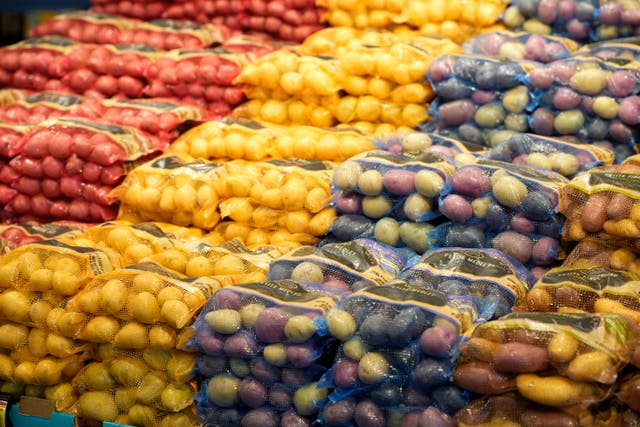 <p>Bags of potatoes are displayed in a supermarket </p>