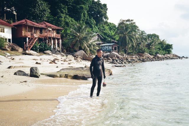 <p>Anuar Abdullah walks along the beach toward a coral nursery </p>