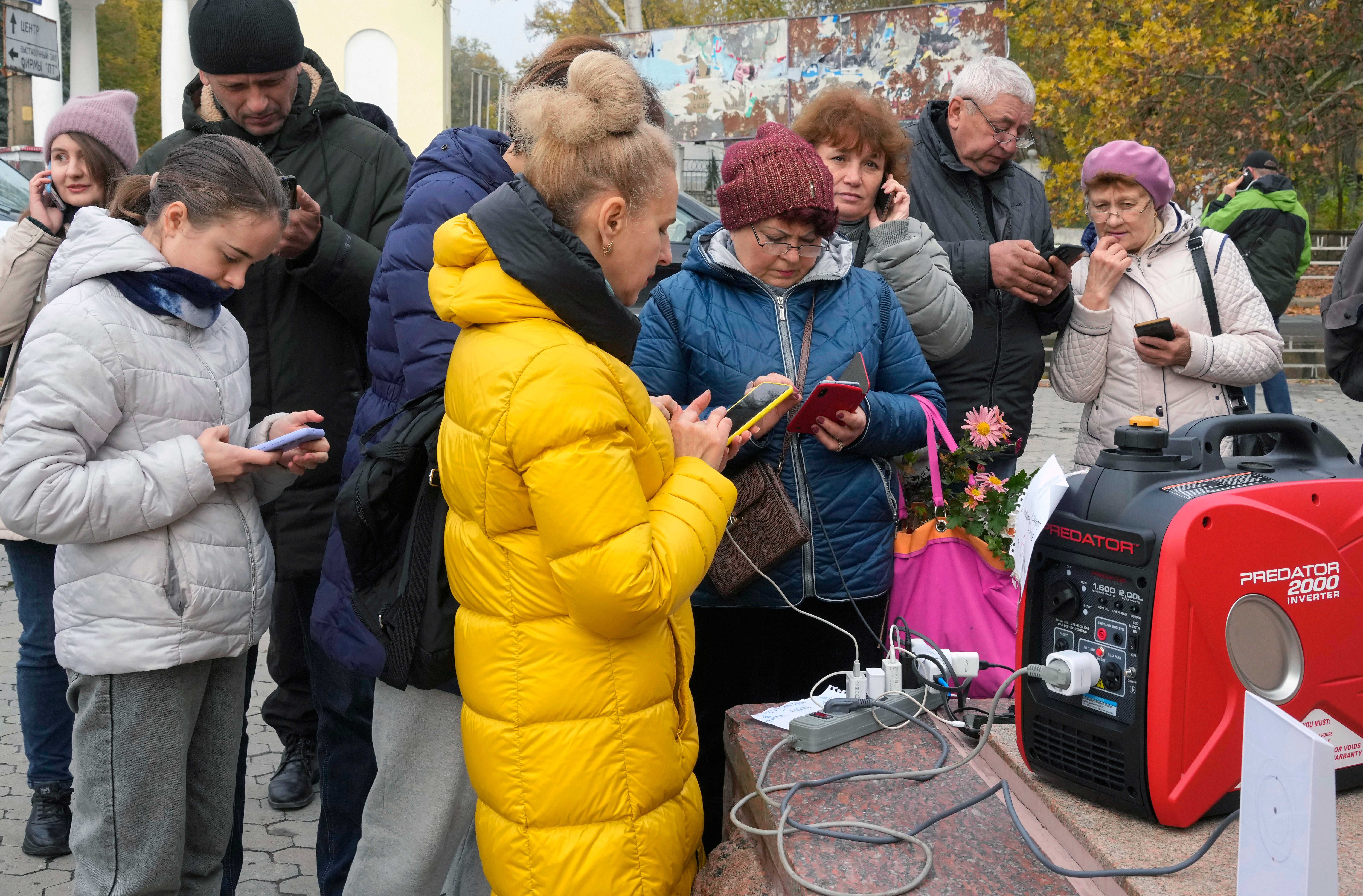 Civilians share a generator to charge their phones in Kherson, Ukraine as retreating Russians bomb power supplies