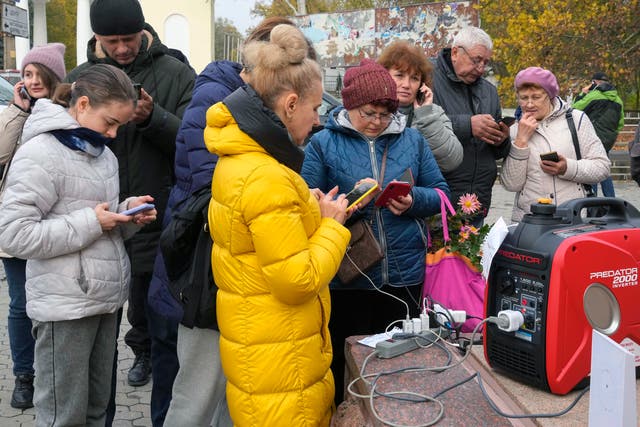<p>Civilians share a generator to charge their phones in Kherson, Ukraine as retreating Russians bomb power supplies</p>