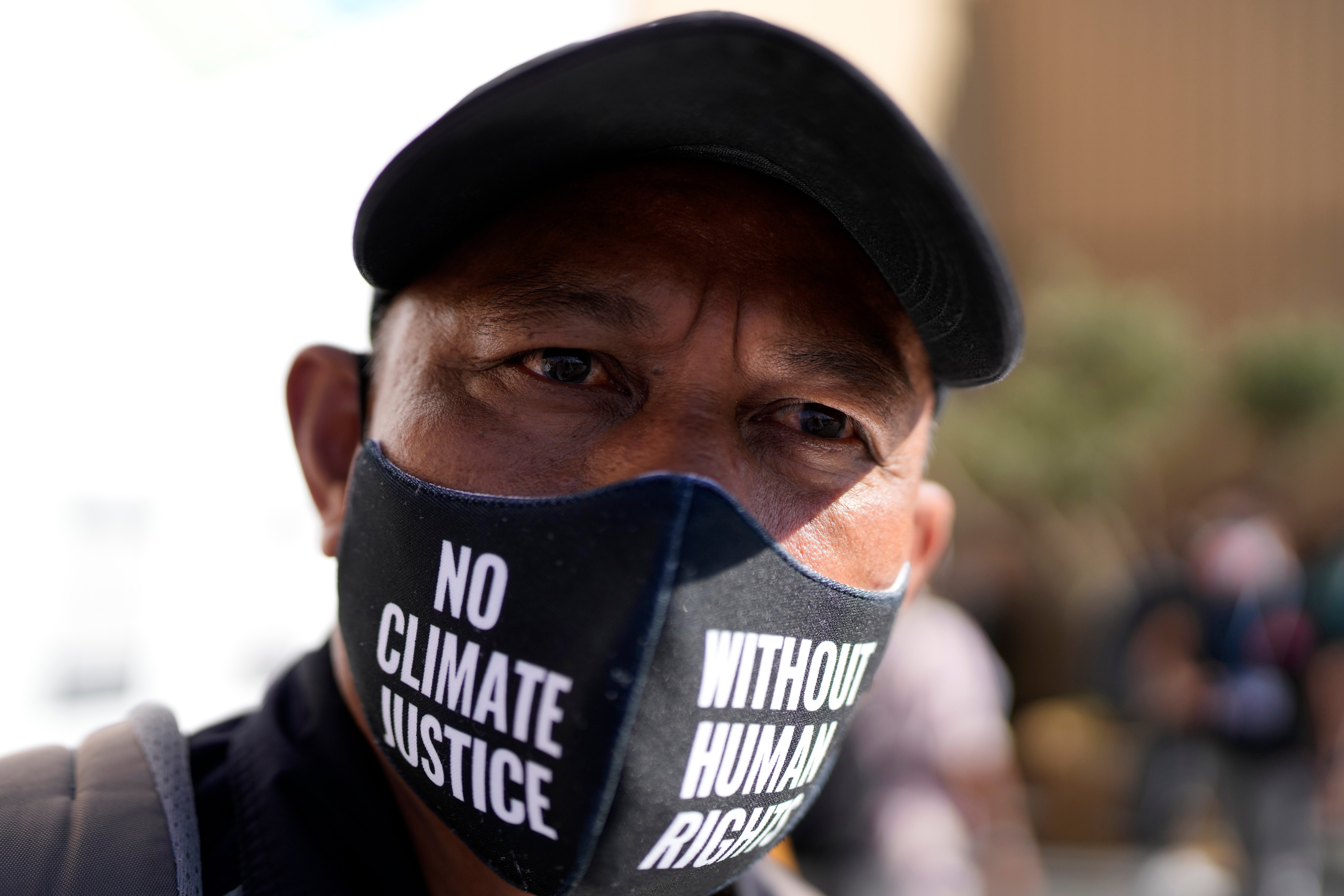 A man wears a face mask during a protest that reads ‘no climate justice without human rights’