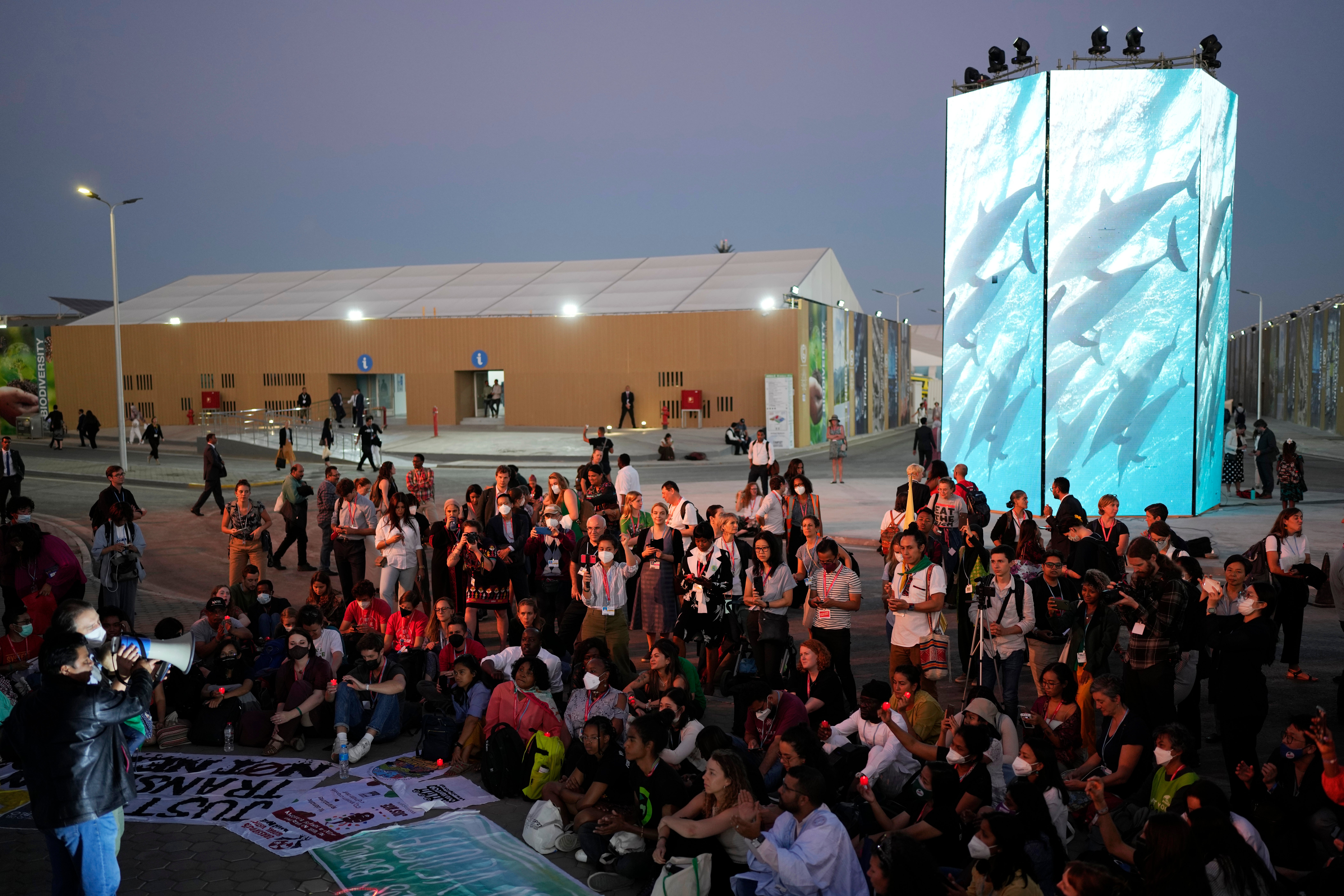 Activists listen to a demonstration at dusk at Cop27 on Friday as the summit ran into overtime