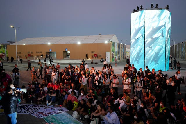 <p>Activists listen to a demonstration at dusk at Cop27 on Friday as the summit ran into overtime </p>
