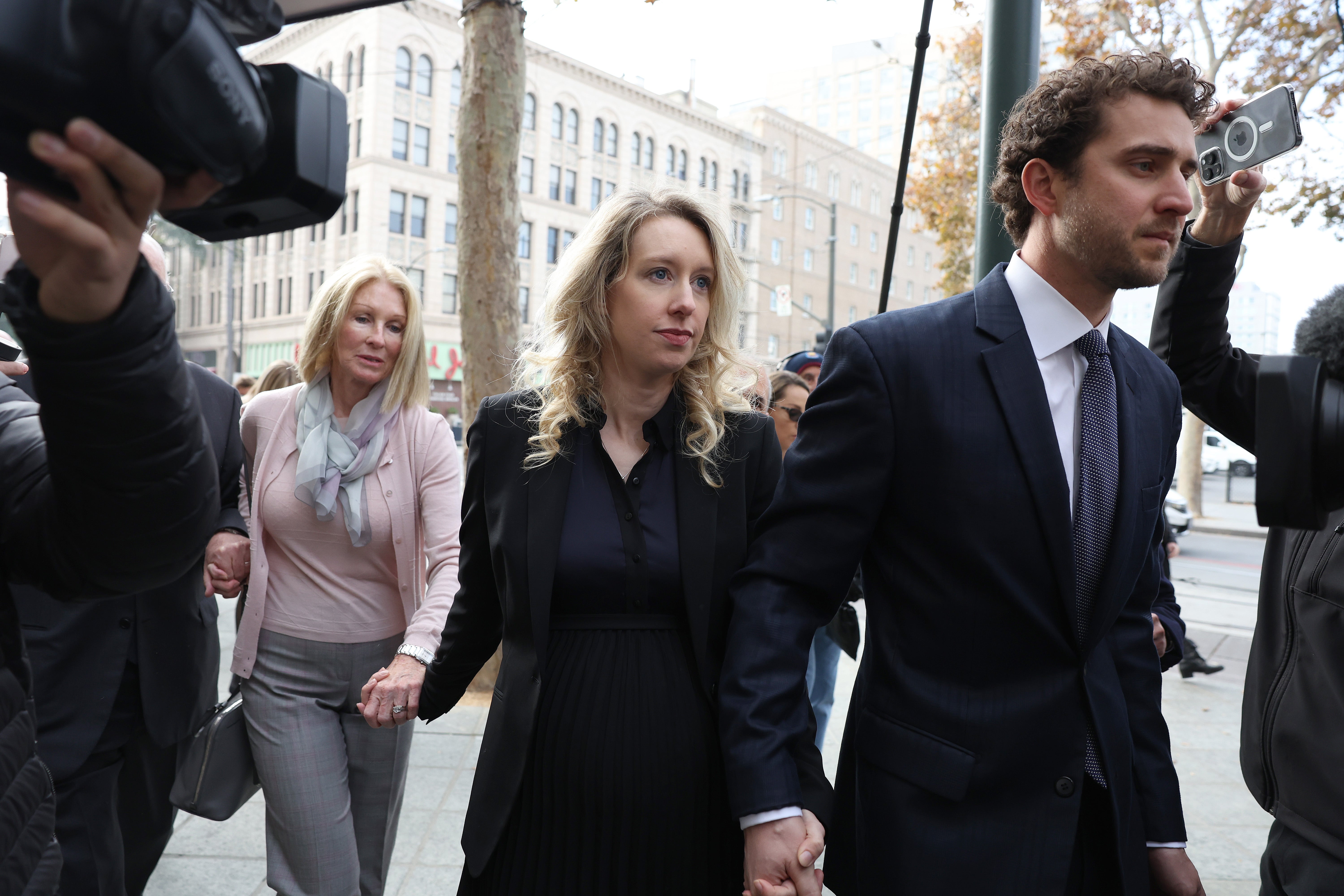 Former Theranos CEO Elizabeth Holmes, centre, arrives at federal court with her partner Billy Evans, right, and mother Noel Holmes on Friday