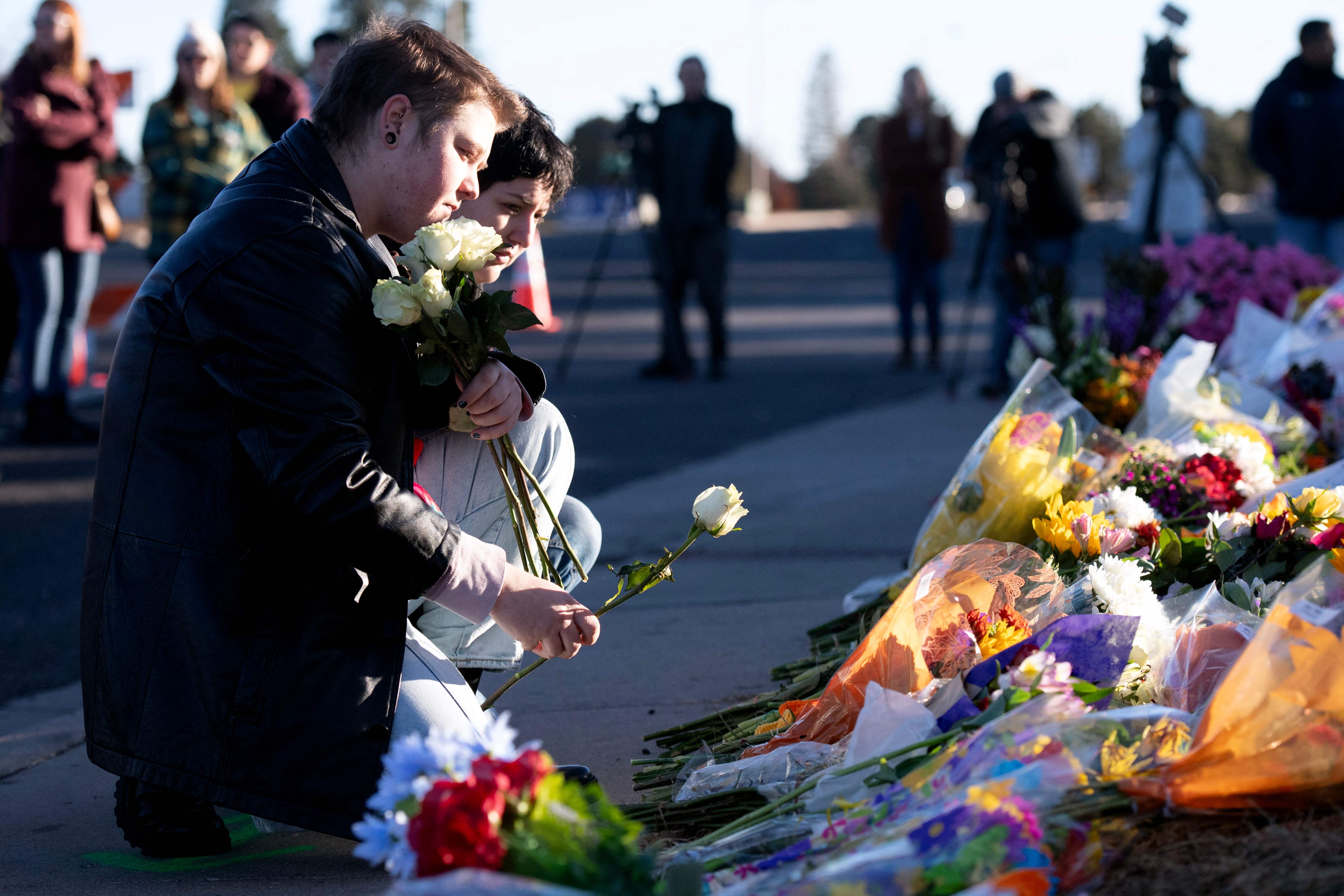Mourners Ren Kurgis and Jessie Pacheco visit a memorial for victims of the Club Q attack on 20 November