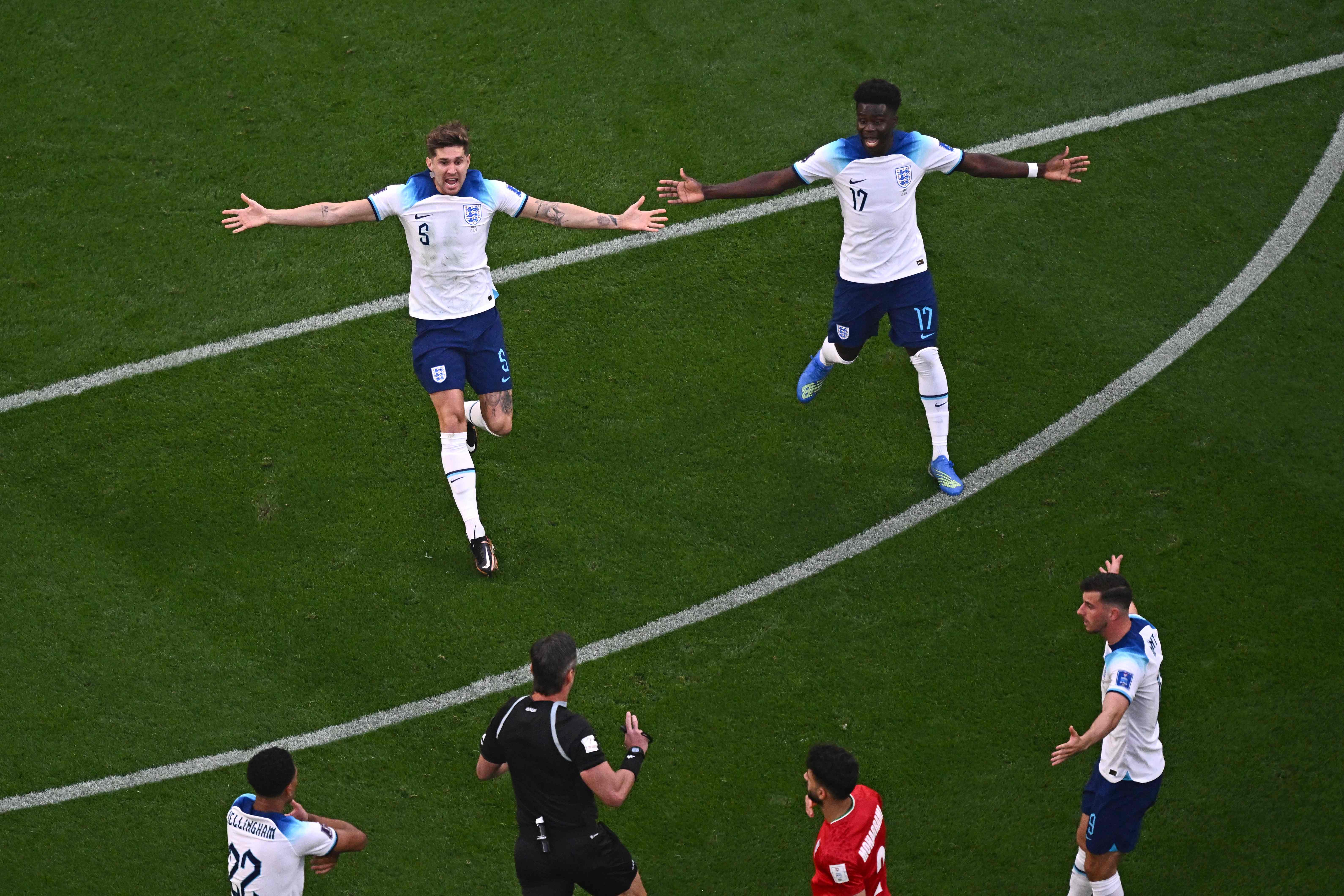 John Stones and forward Bukayo Saka run toward the ref