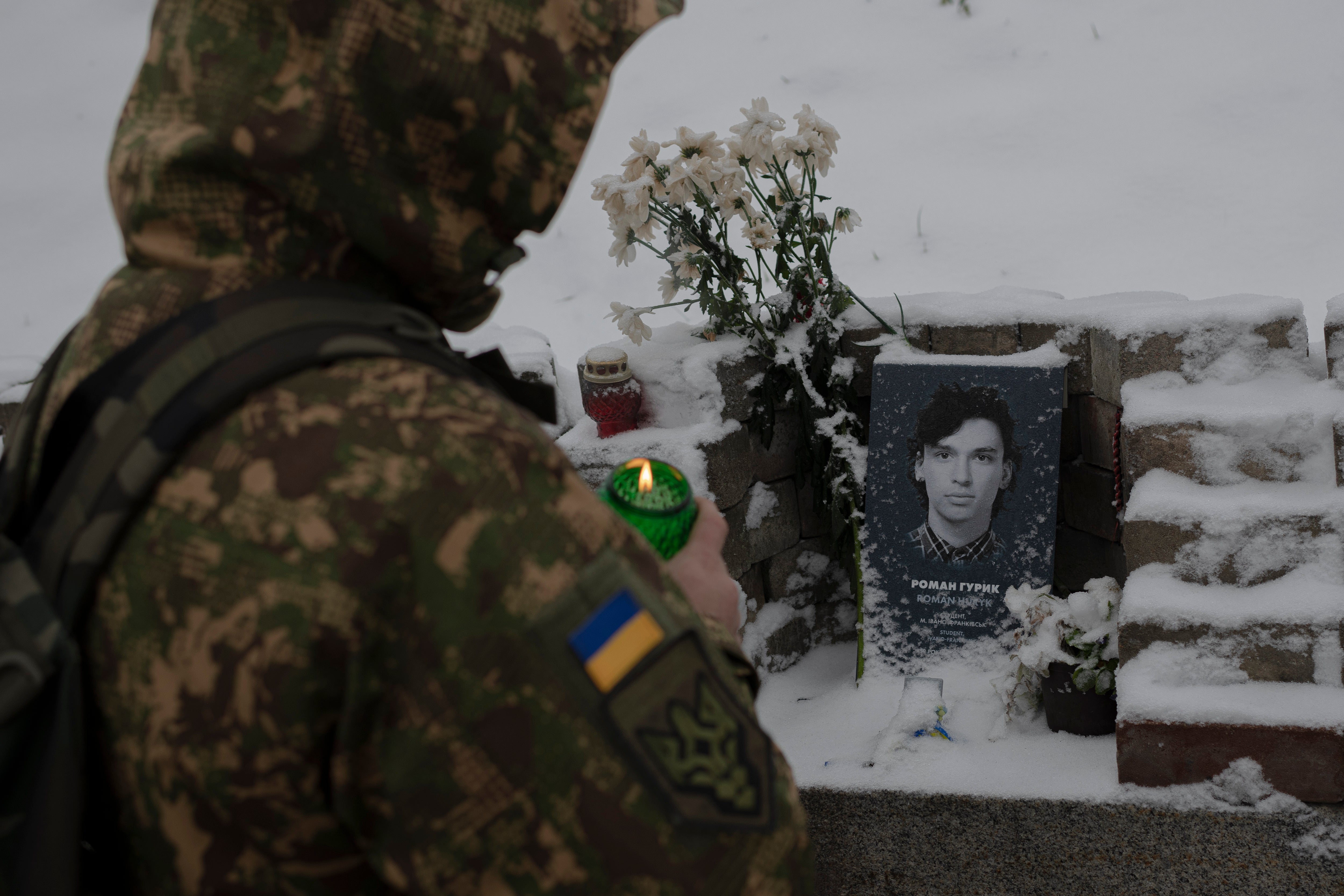 <p>A Ukrainian serviceman lights a candle at a memorial in Kyiv</p>