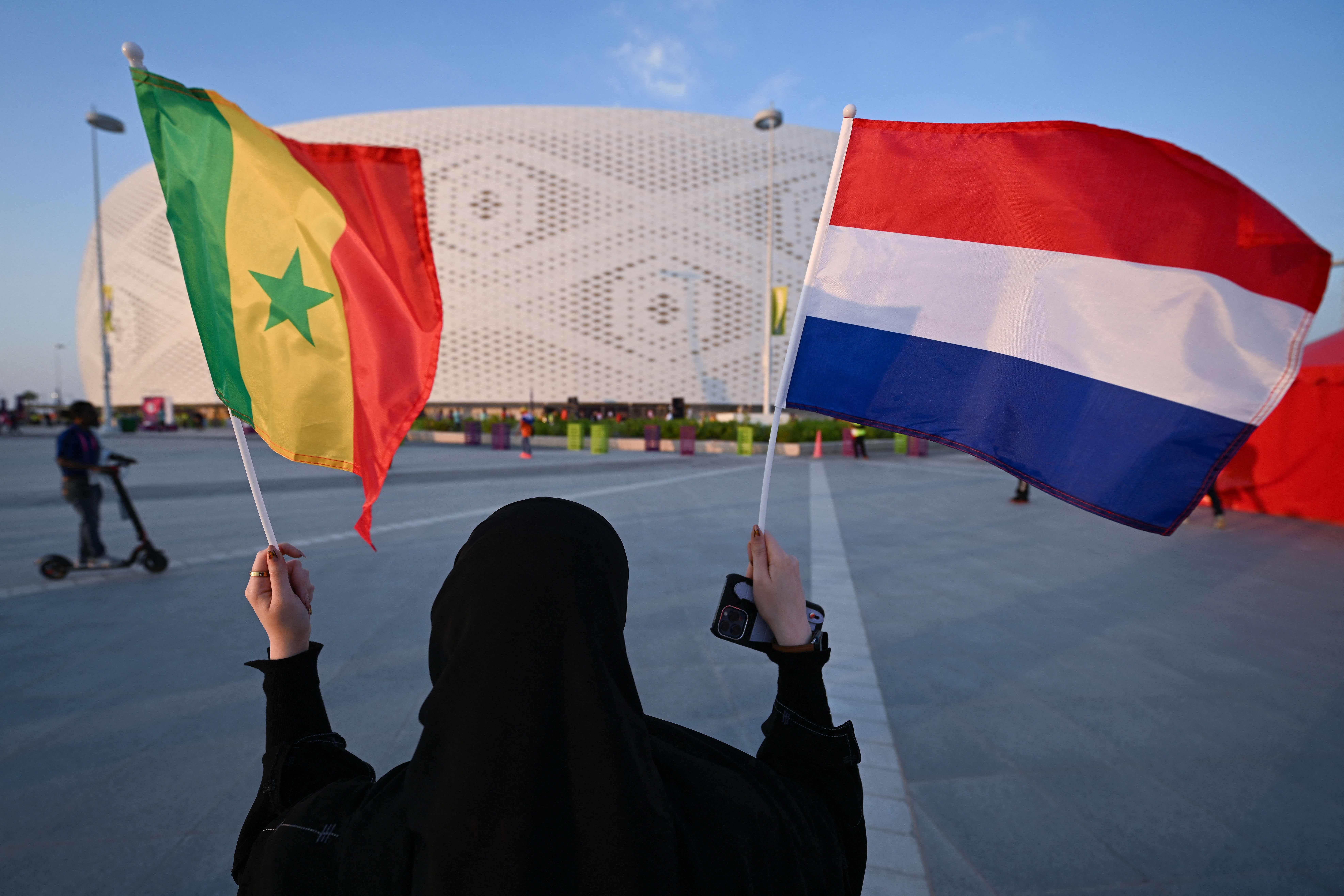 A woman holds up flags of Senegal and the Netherlands ahead of the Group A match