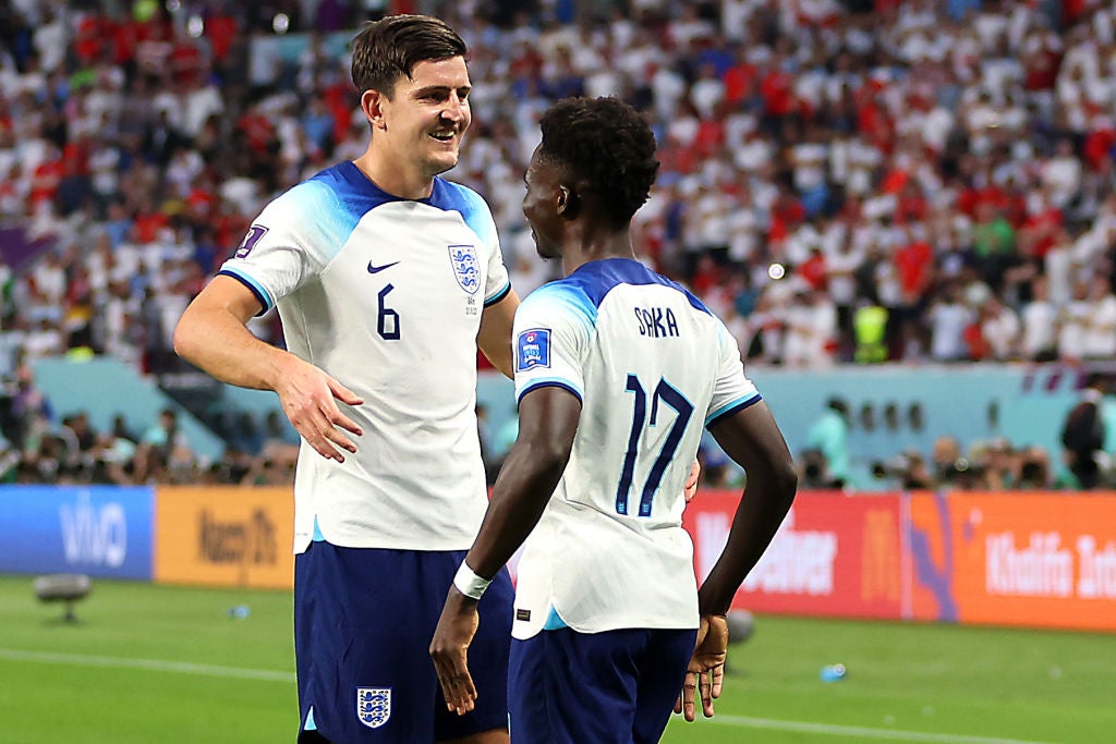 Bukayo Saka celebrates with Harry Maguire after scoring their team's second goal