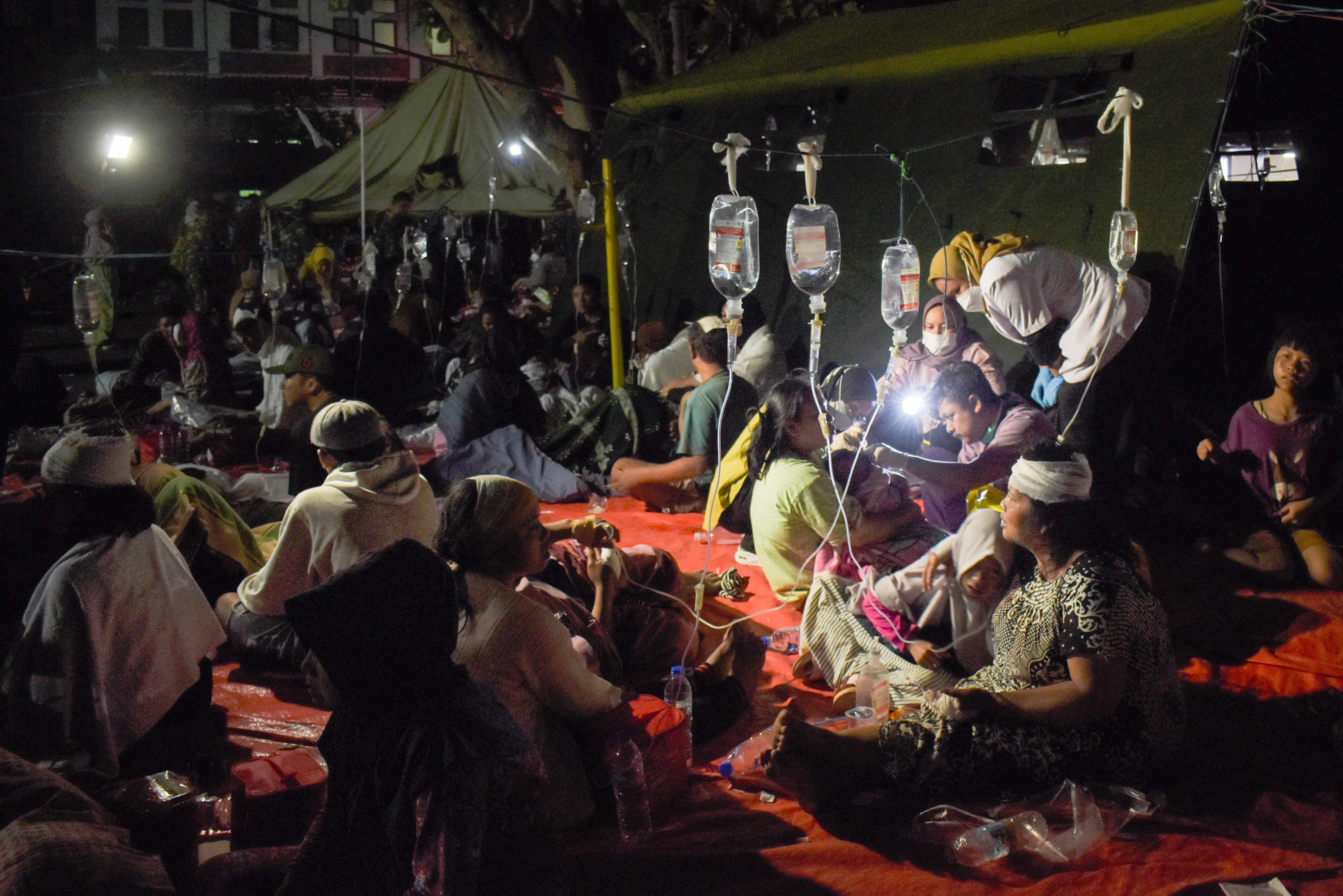 Wounded survivors of an earthquake are treated in the yard of a hospital in Cianjur