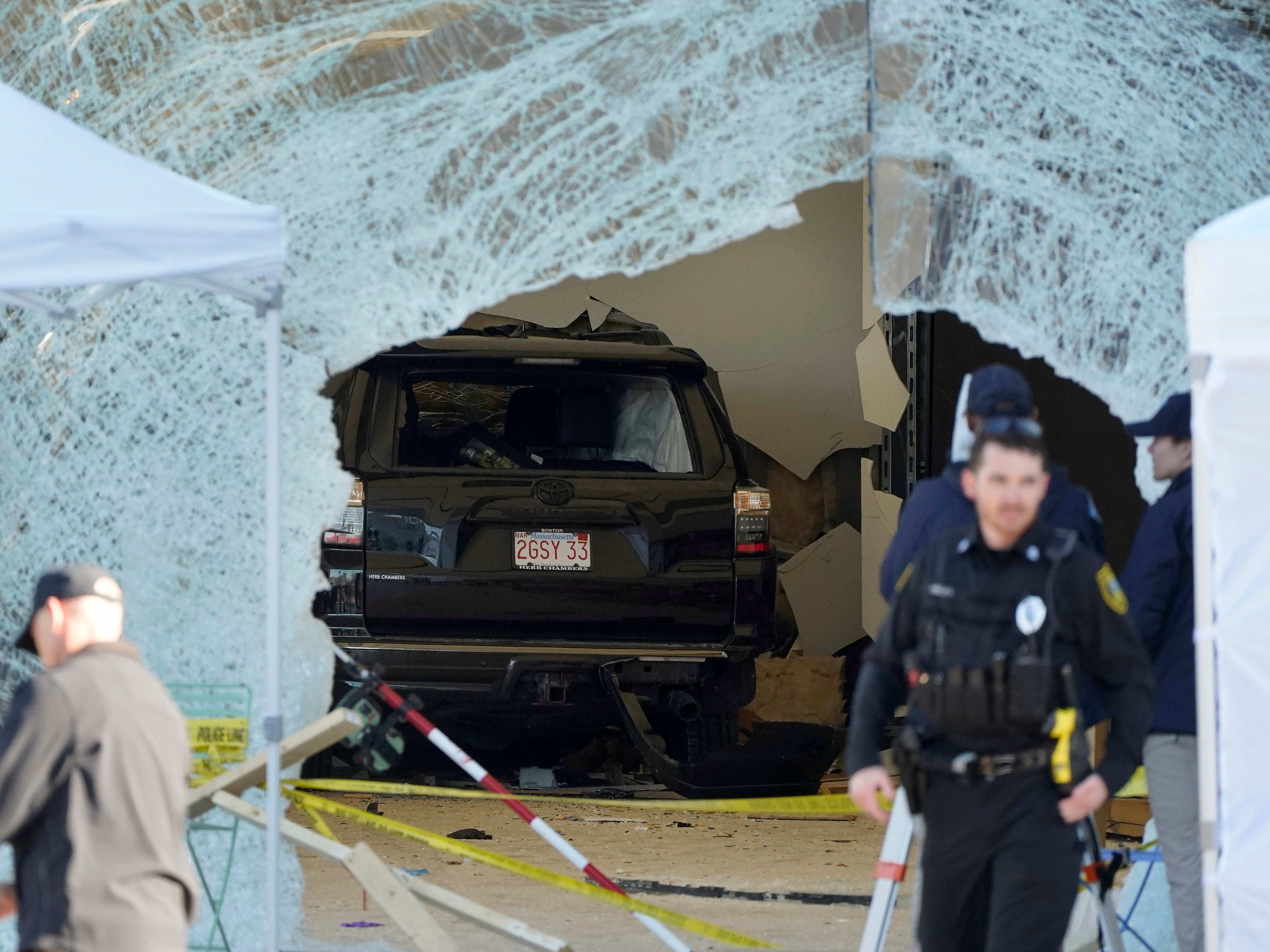 An SUV rests inside an Apple store behind a large hole in the glass front of the store, Monday, Nov. 21, 2022, in Hingham, Mass