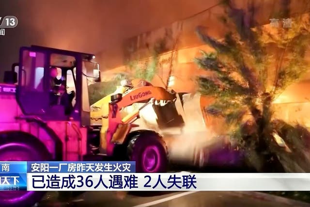<p>In this image taken from video footage run by China's CCTV, rescuers use a bulldozer to knock over a wall at a fire at an industrial wholesaler in Anyang in central China's Henan province on Monday, 21 November 2022</p>
