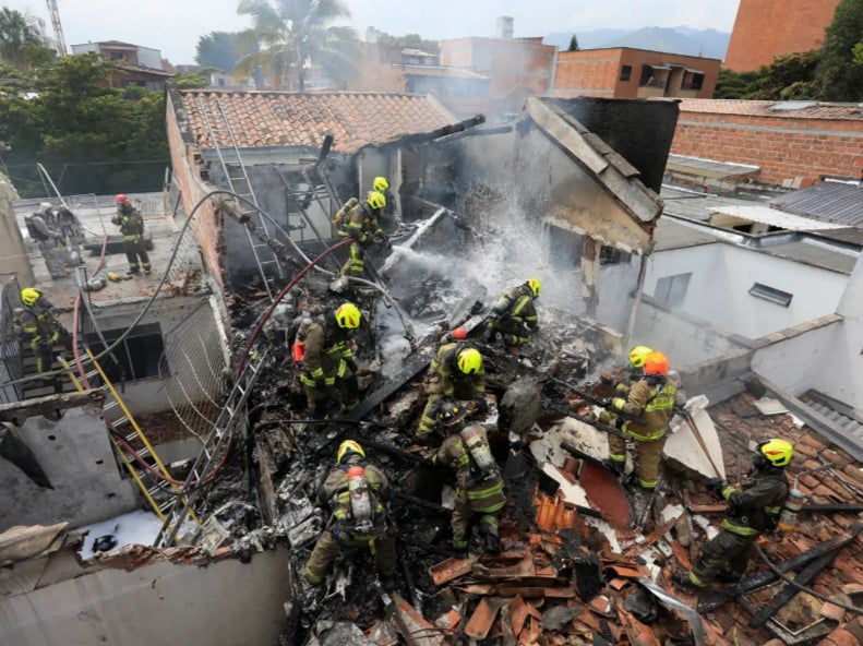 Firefighters at the scene of the crash in Medellin, Colombia where an aircraft carrying eight people crashed and killed all on board
