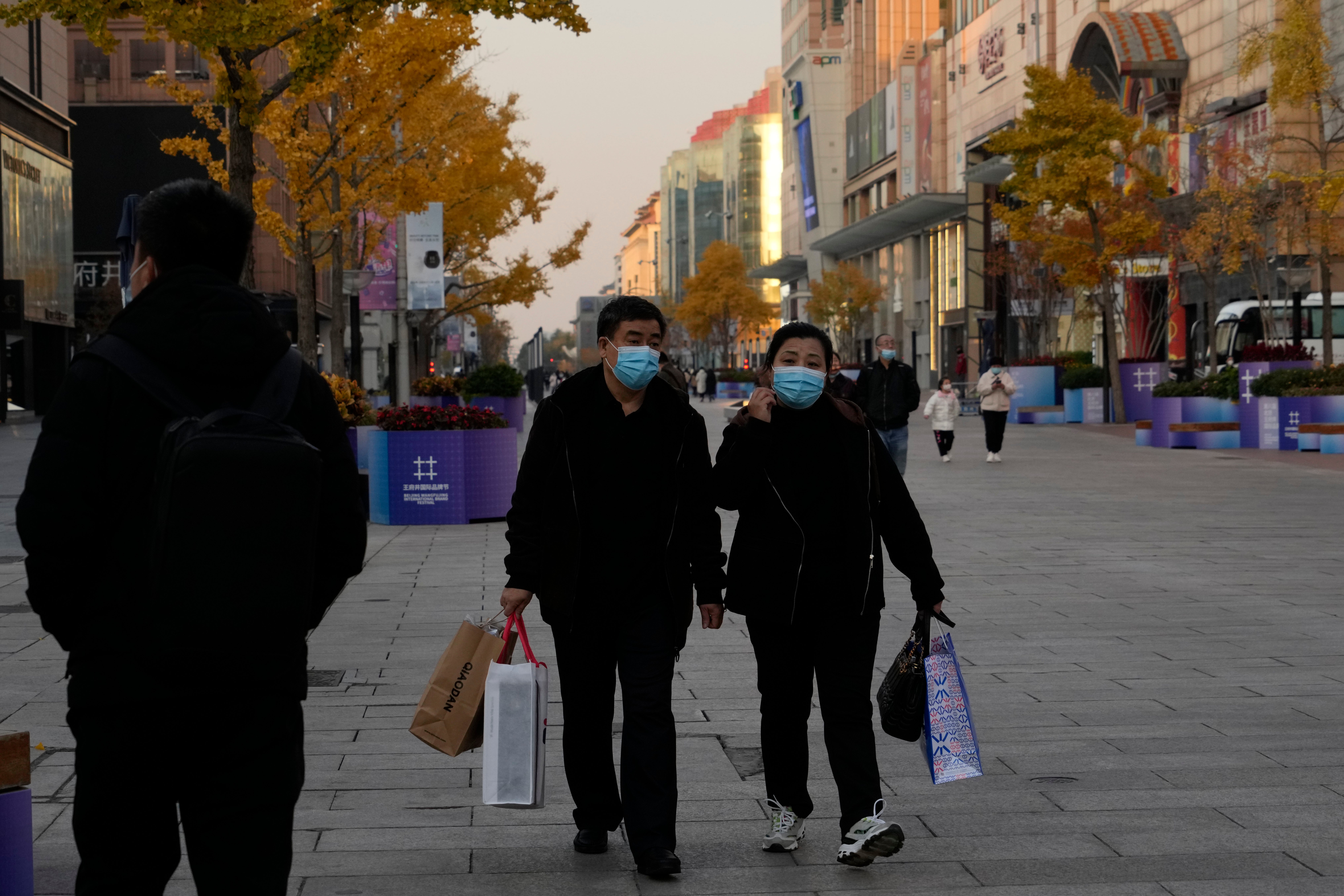 File. Residents carry bags as they visit the Wangfujing shopping street in Beijing, Monday, 14 November 2022