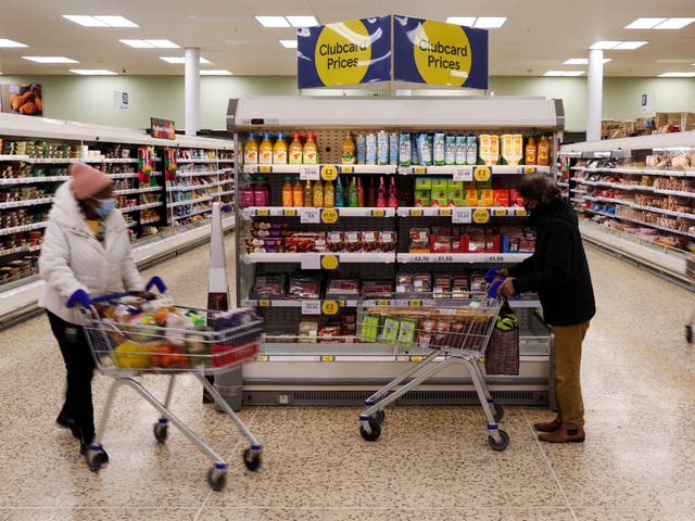 <p>Clubcard branding is seen next to shoppers inside a branch of a Tesco Extra Supermarket in London</p>