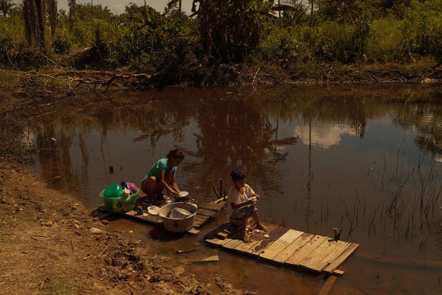 <p>Antonia Franco dos Santos and her grandson wash dishes in a nearby pond </p>