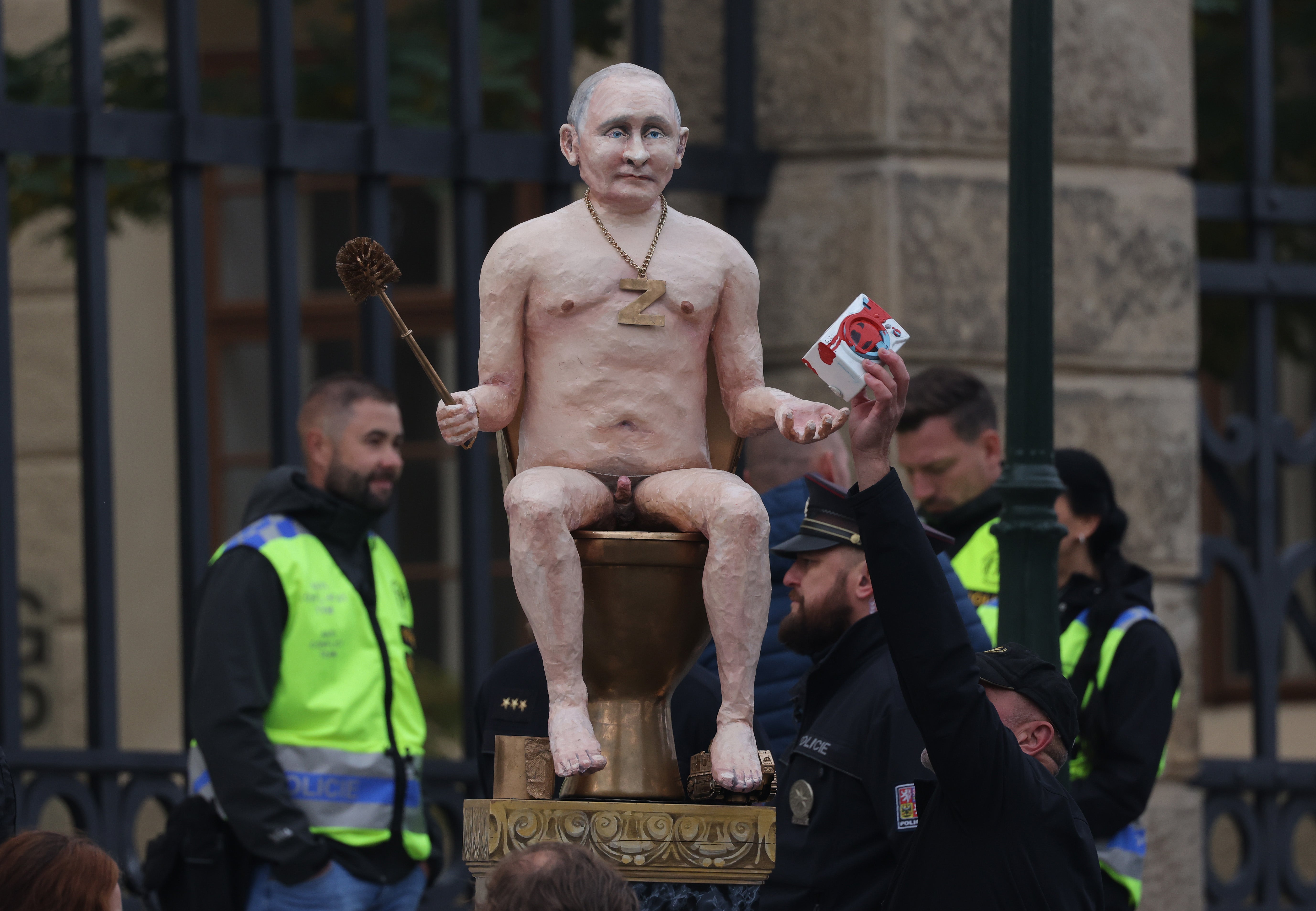 The Putin statue is seen gripping a golden toilet brush and toy washing machine pouring with fake blood