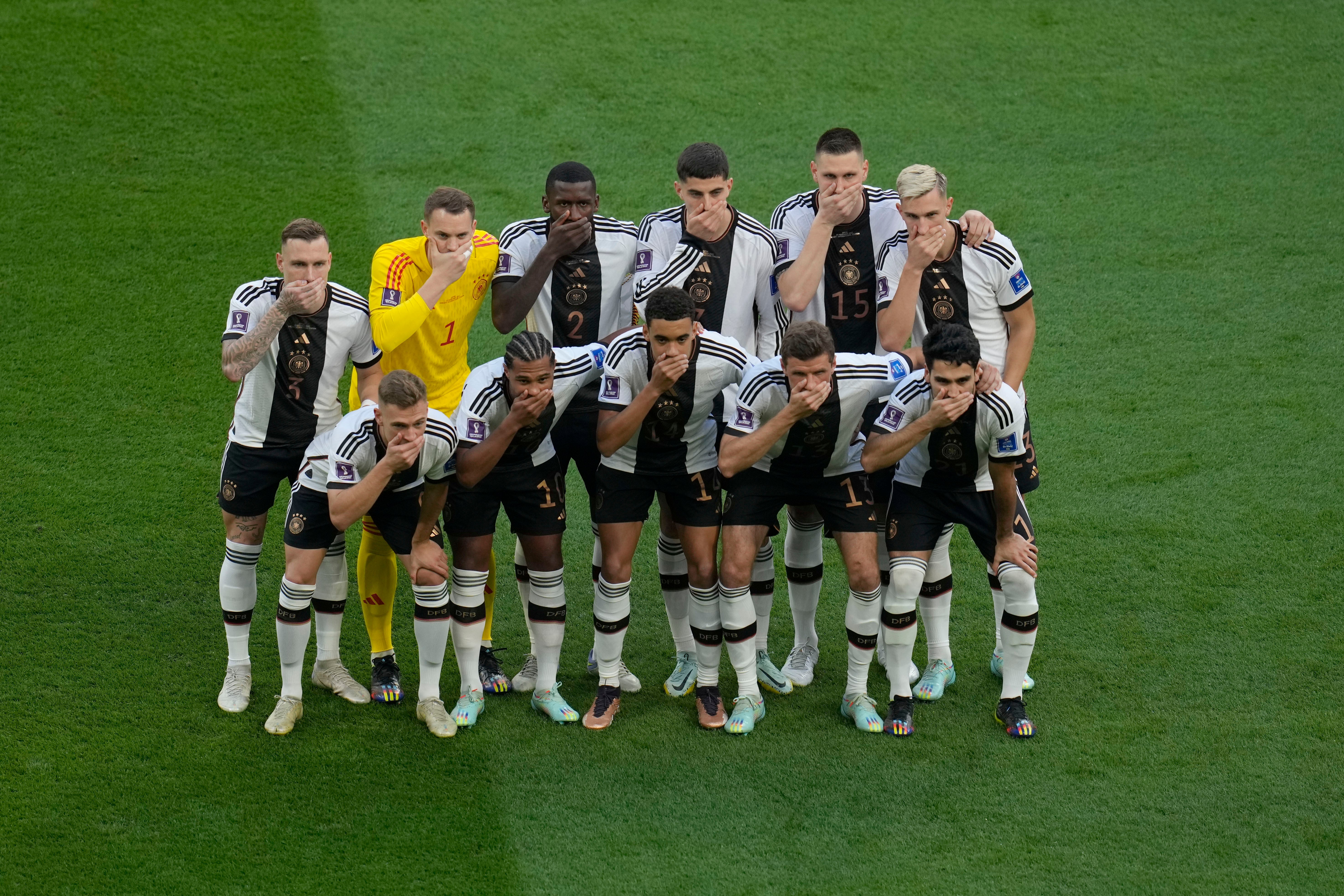 Germany’s football team players cover their mouths before the World Cup group E match against Japan