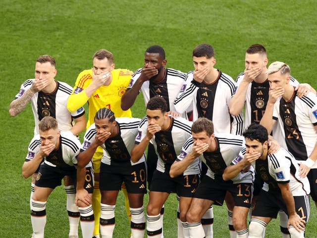 <p>Germany players cover their mouths with their hands as they line up to face Japan</p>