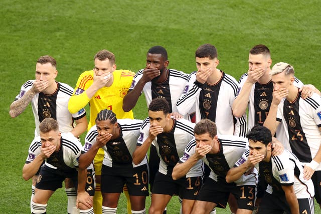 <p>Germany players cover their mouths with their hands as they line up to face Japan</p>