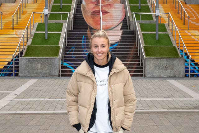 <p>Leah Williamson unveils a mural by artist Charlotte Archer on the Spanish Steps of Wembley Stadium, which depicts Helen Hardy - founder of Manchester Laces</p>