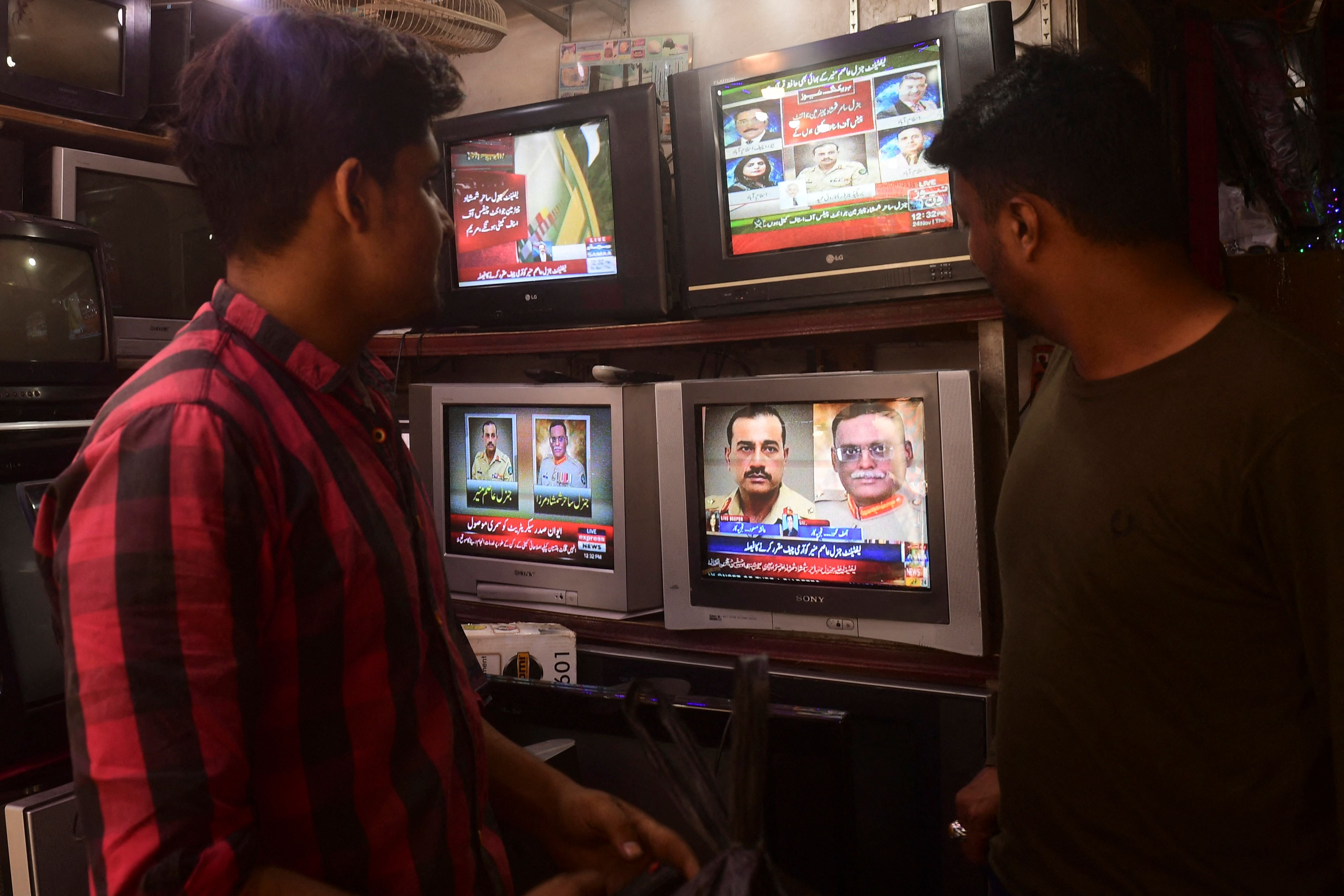 People watch a news television broadcast of the nomination of the next Pakistan's army Chief General Syed Asim Munir at a market in Karachi