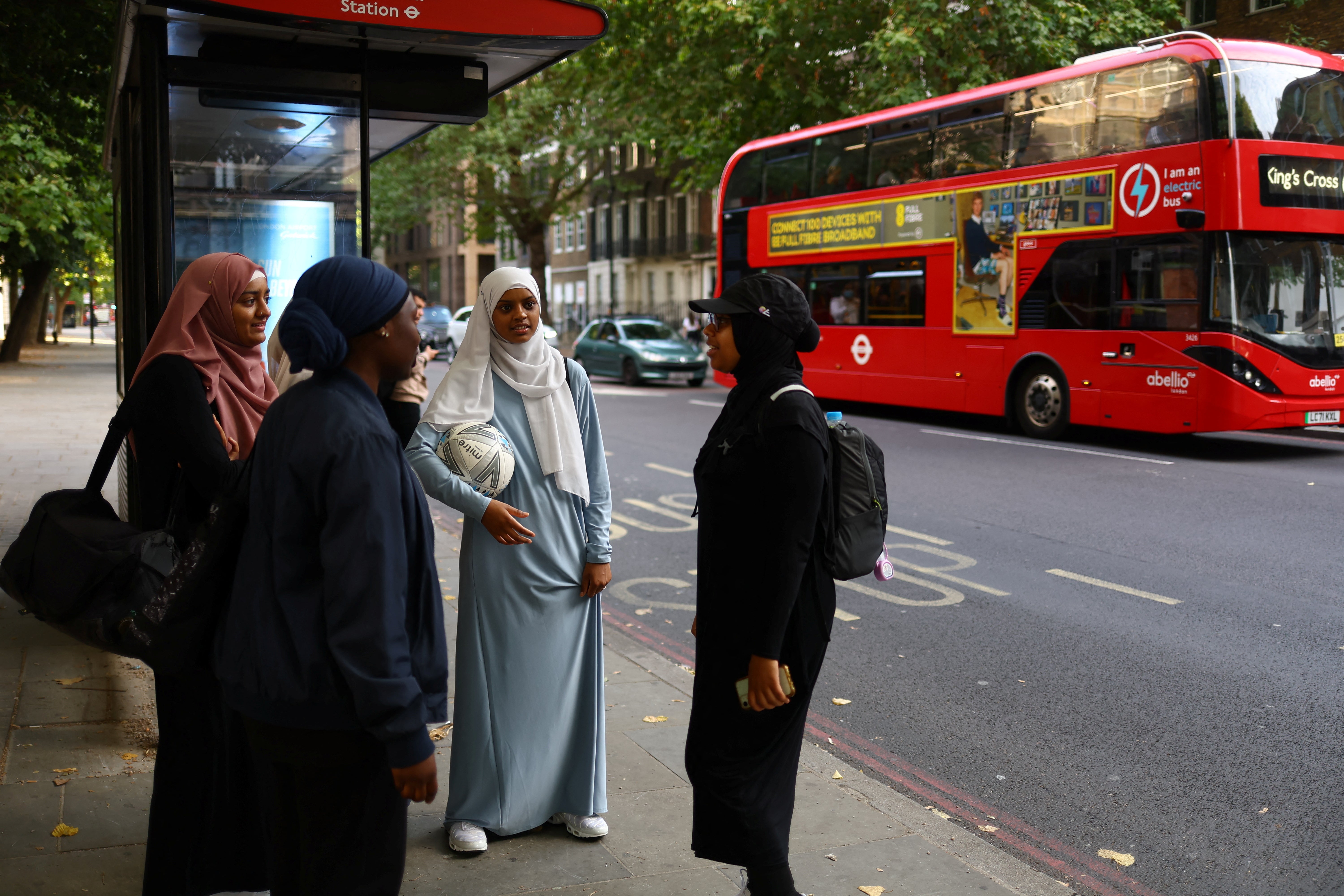 Team members Atiya, 24, Kamara and Amilah, 15, wait for the bus home after playing in the Ladies Super Liga tournament