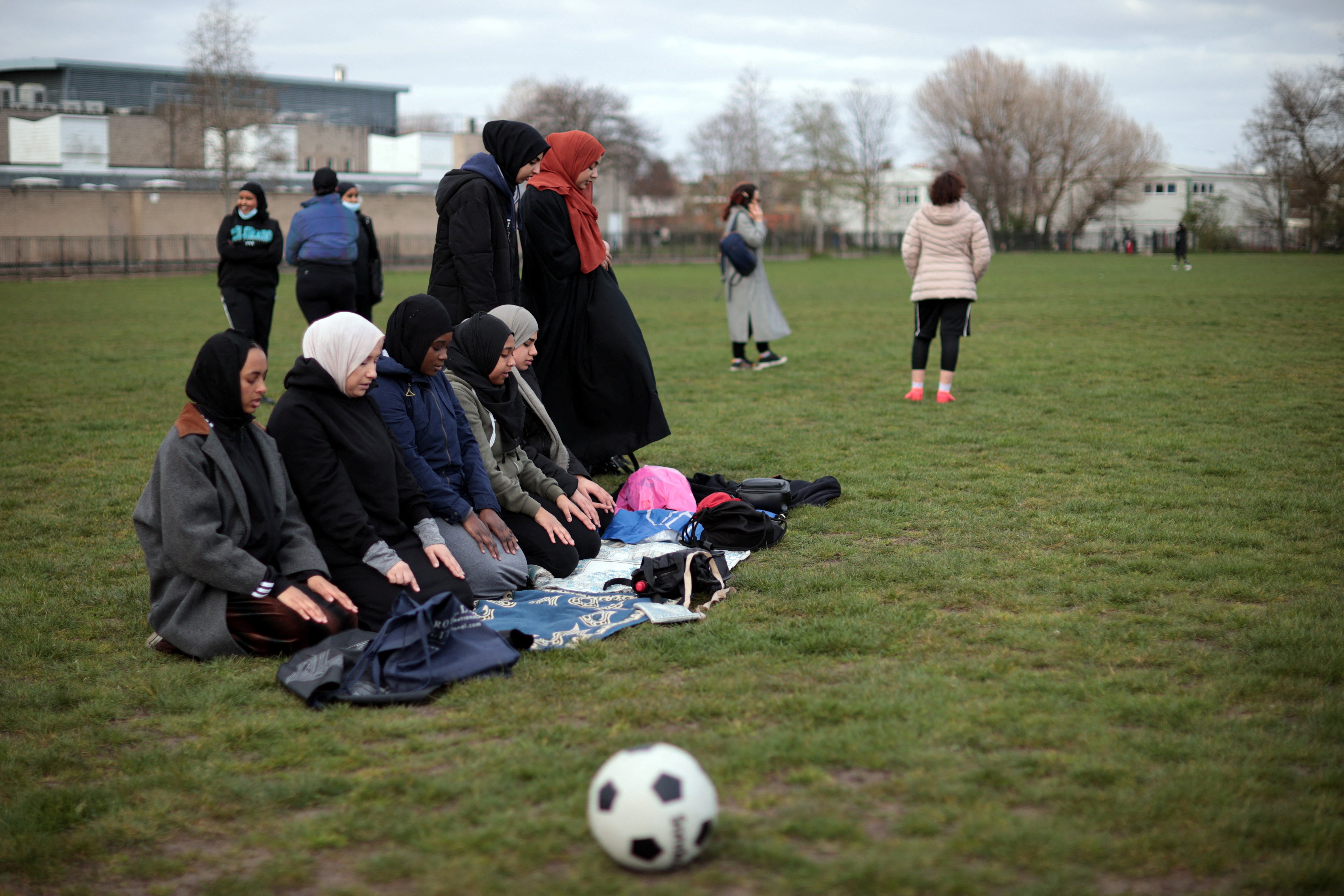 Teammates pray during a training session in King George’s Park in London