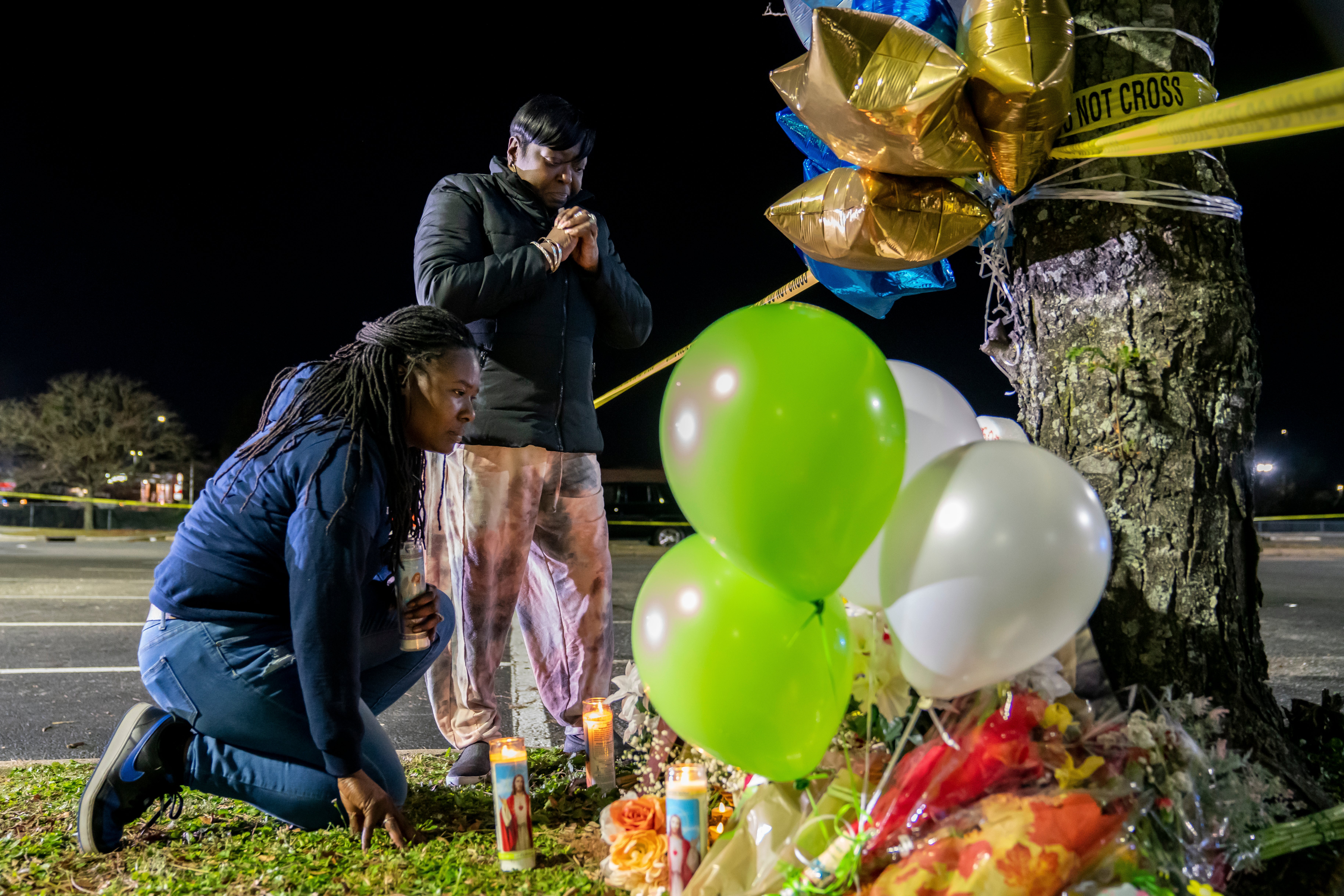 Lashana Hicks, left, joins other mourners at a memorial for those killed in fatal shooting at Chesapeake Walmart