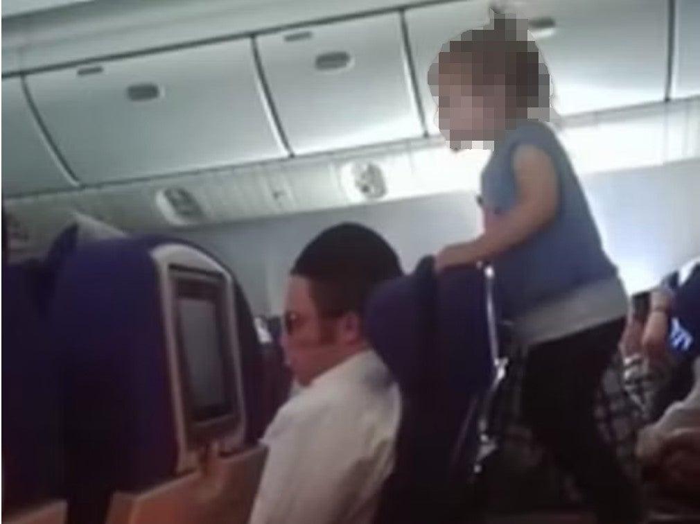 A little girl repeatedly jumps up and down on a tray table during a flight