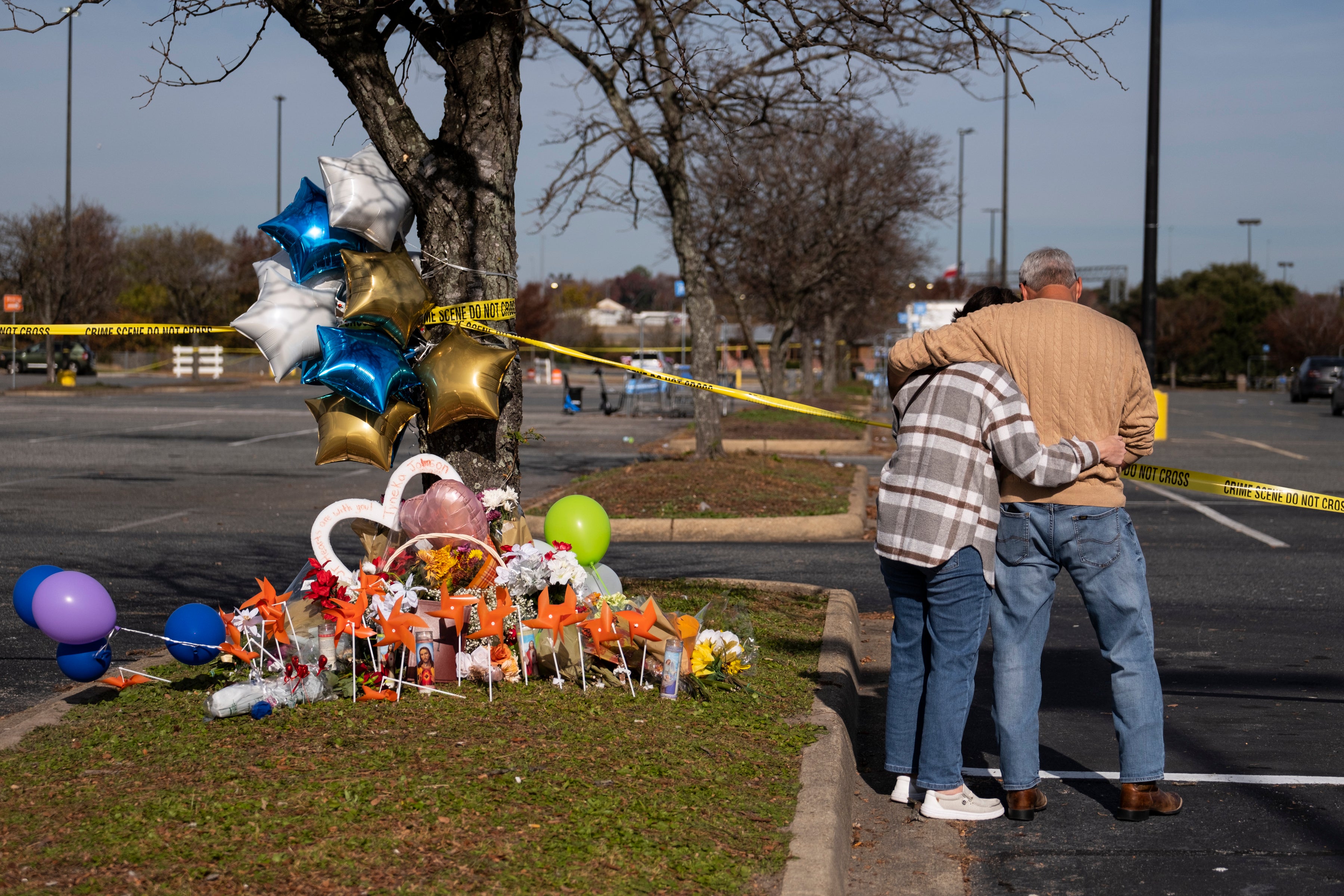 Debbie (left) and Chet Barnett place flowers at a memorial outside of the Chesapeake Walmart on 24 November