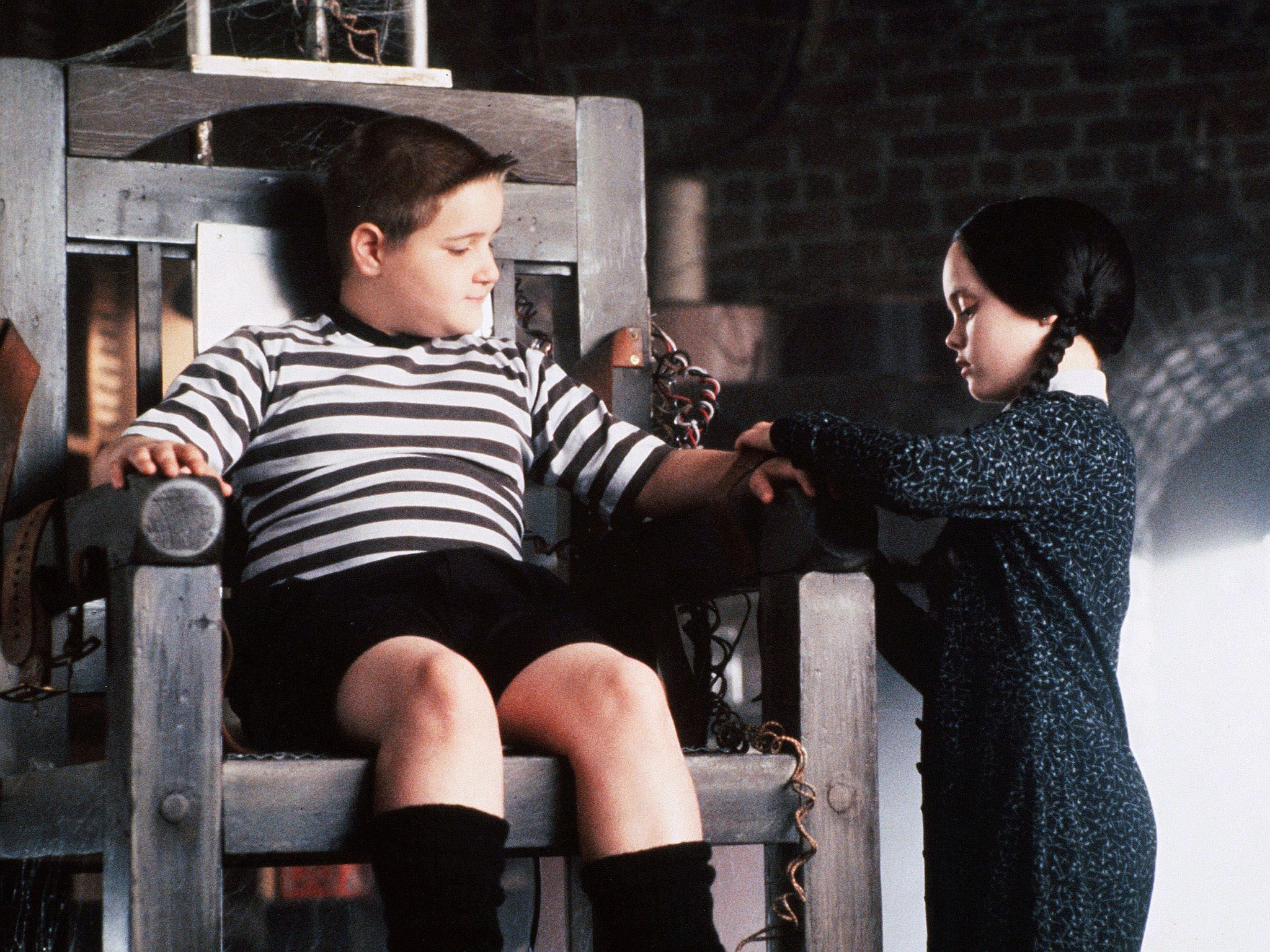 Christina Ricci’s Wednesday straps her brother Pugsley (Jimmy Workman) into an electric chair in ‘The Addams Family’