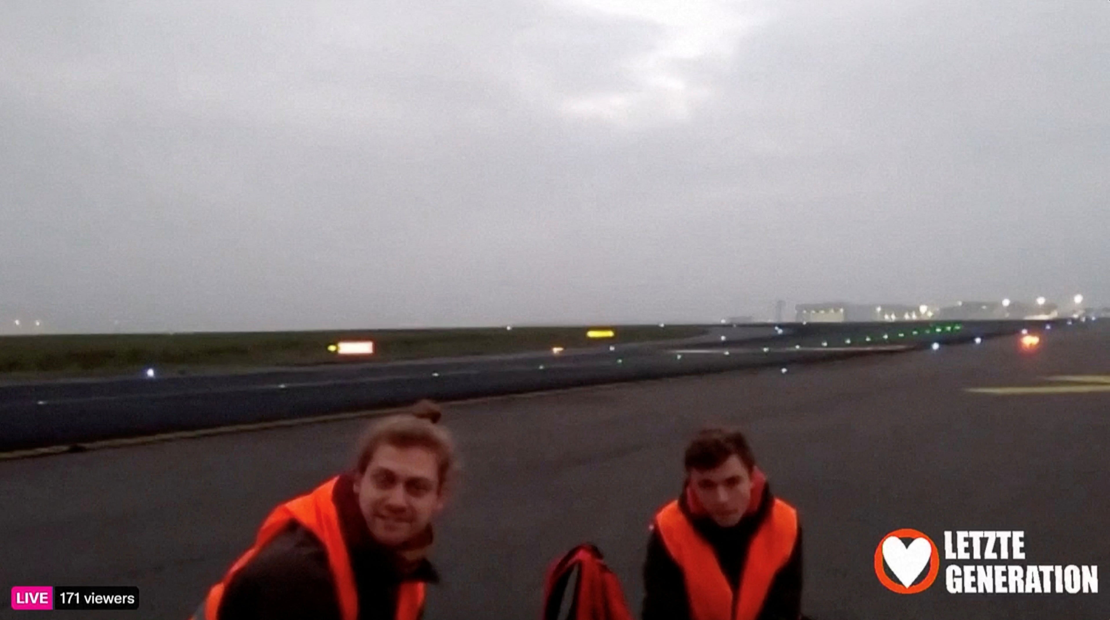 Climate activists glue themselves to a runway at the Berlin Brandenburg Airport (BER) during a protest