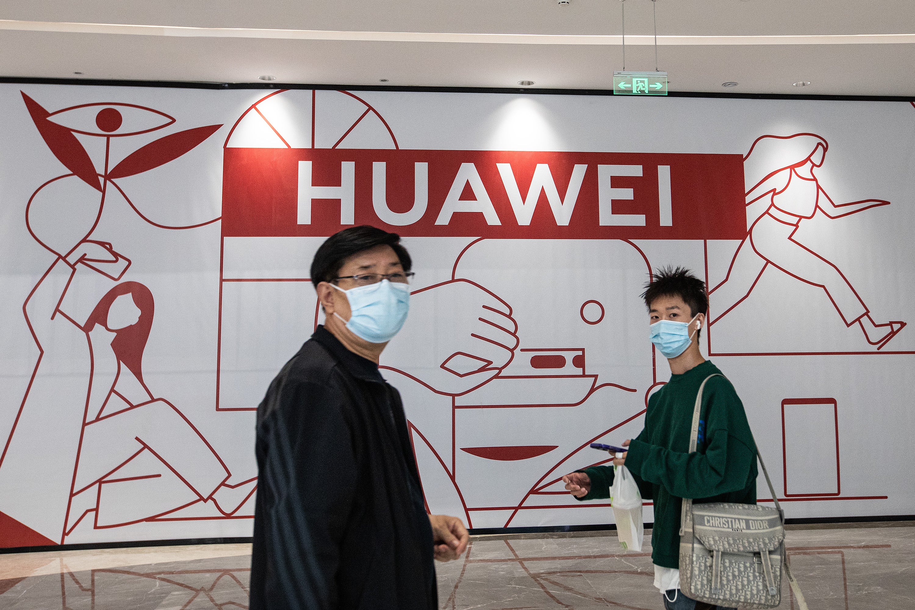 Visitors walk past a Huawei store preparing to open at the Wushang Dream Plaza mall in Wuhan, China