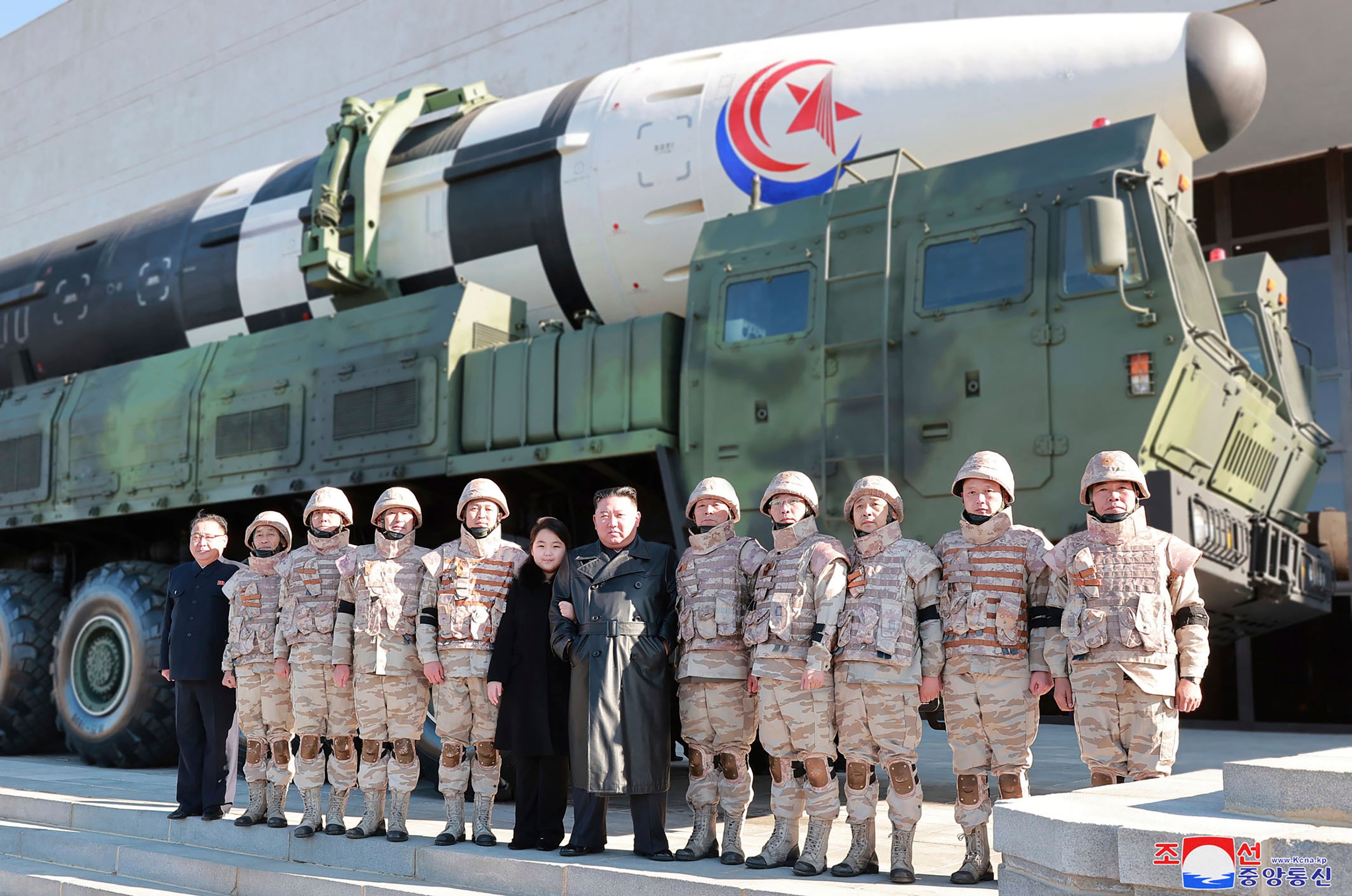 North Korean leader Kim Jong Un, center, and his daughter, center left, pose with soldiers for a photo, in front of what it says a Hwasong-17 intercontinental ballistic missile, at unidentified location in North Korea