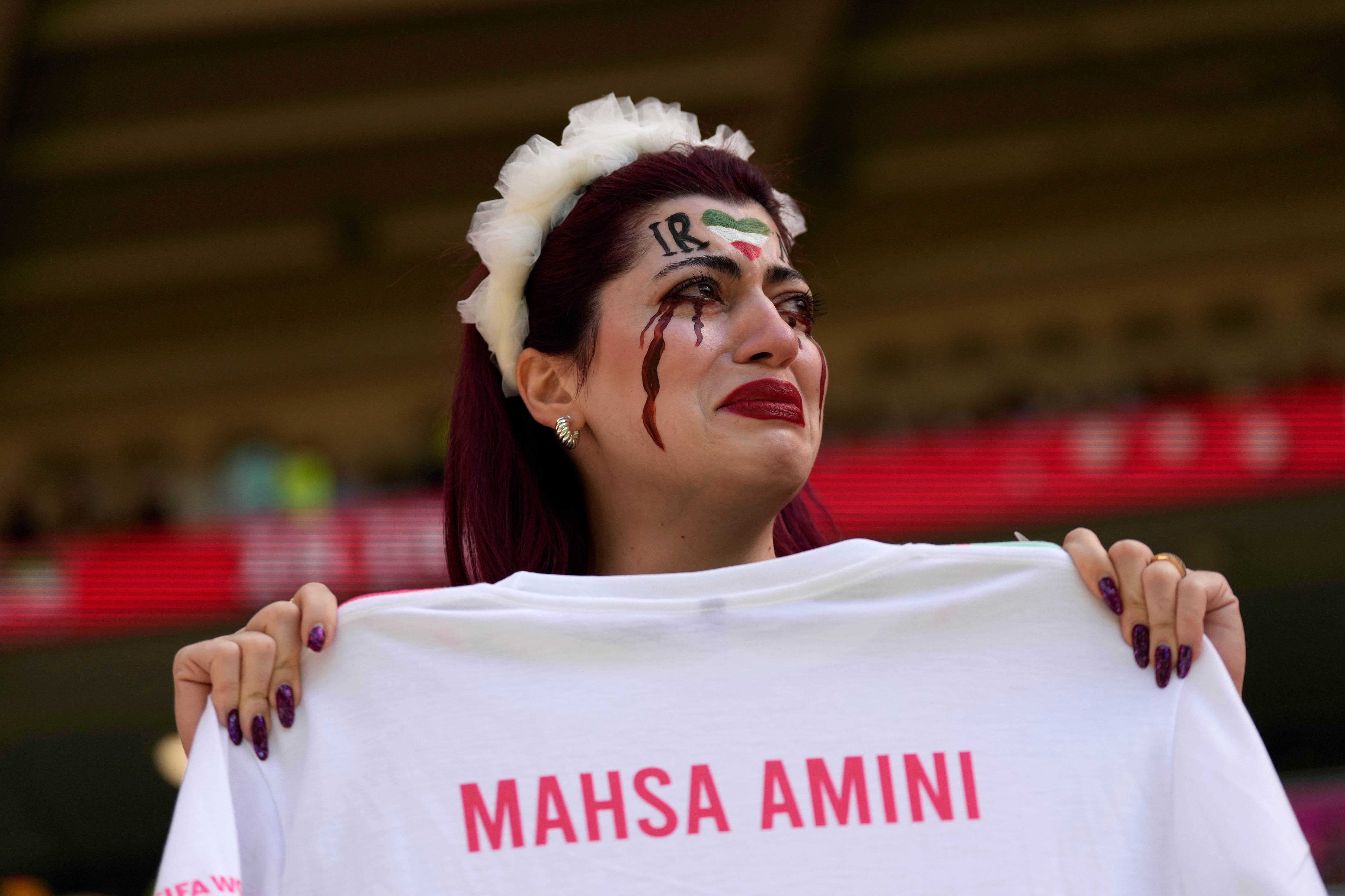 An Iran team supporter cries as she holds a shirt that reads ‘Mahsa Amini’ before Iran’s victory over Wales