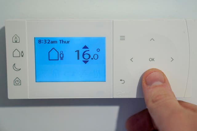 A homeowner turning down the temperature of a central heating thermostat (Andrew Matthews/PA)