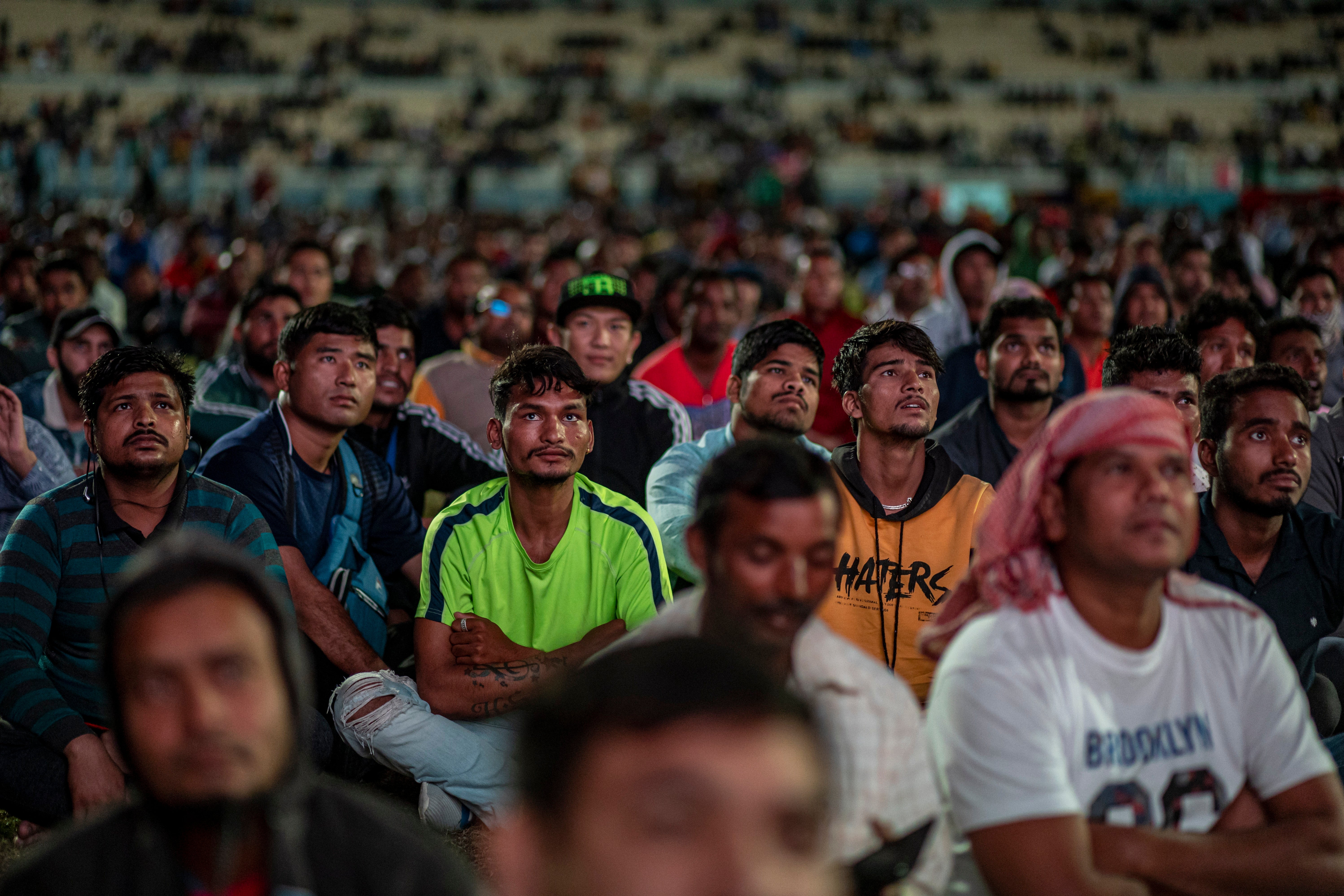 <p>Migrant workers watch the World Cup at the at the free-entry Industrial Area Fan Zone in Doha</p>