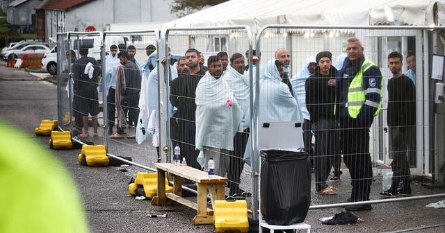 <p>People inside a fenced off area inside the migrant processing centre in Manston earlier this month </p>