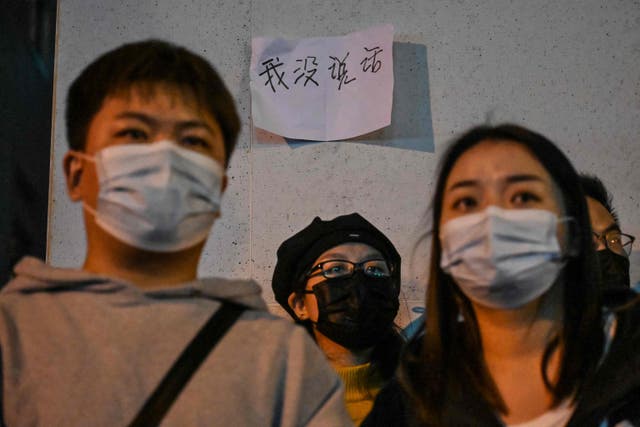 <p>Protesters stand beneath a sign that reads, ‘I didn’t say anything’, in Shanghai on Sunday</p>