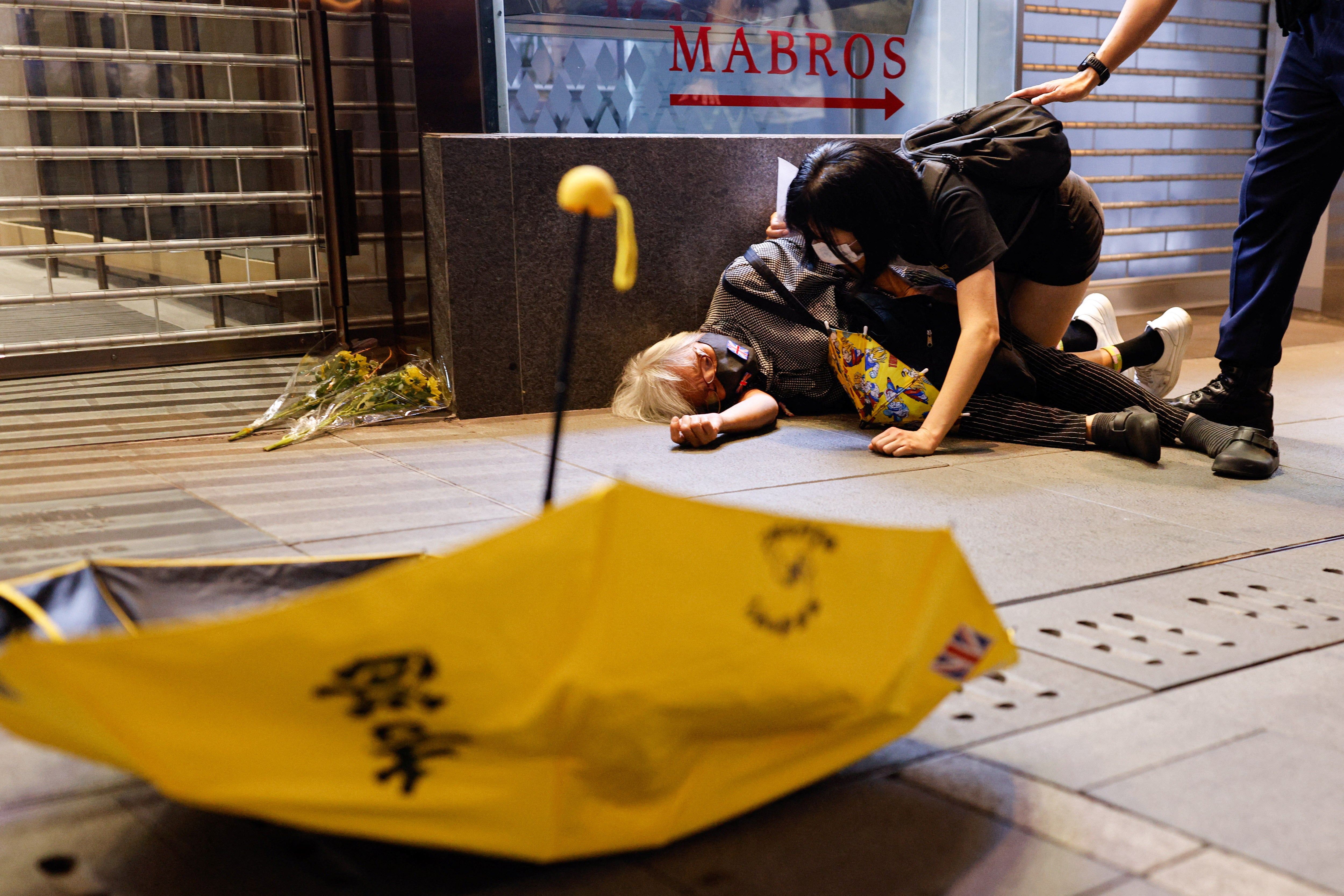 A protester lies on the ground in Hong Kong after being pushed during demonstrations against Covid on mainland China