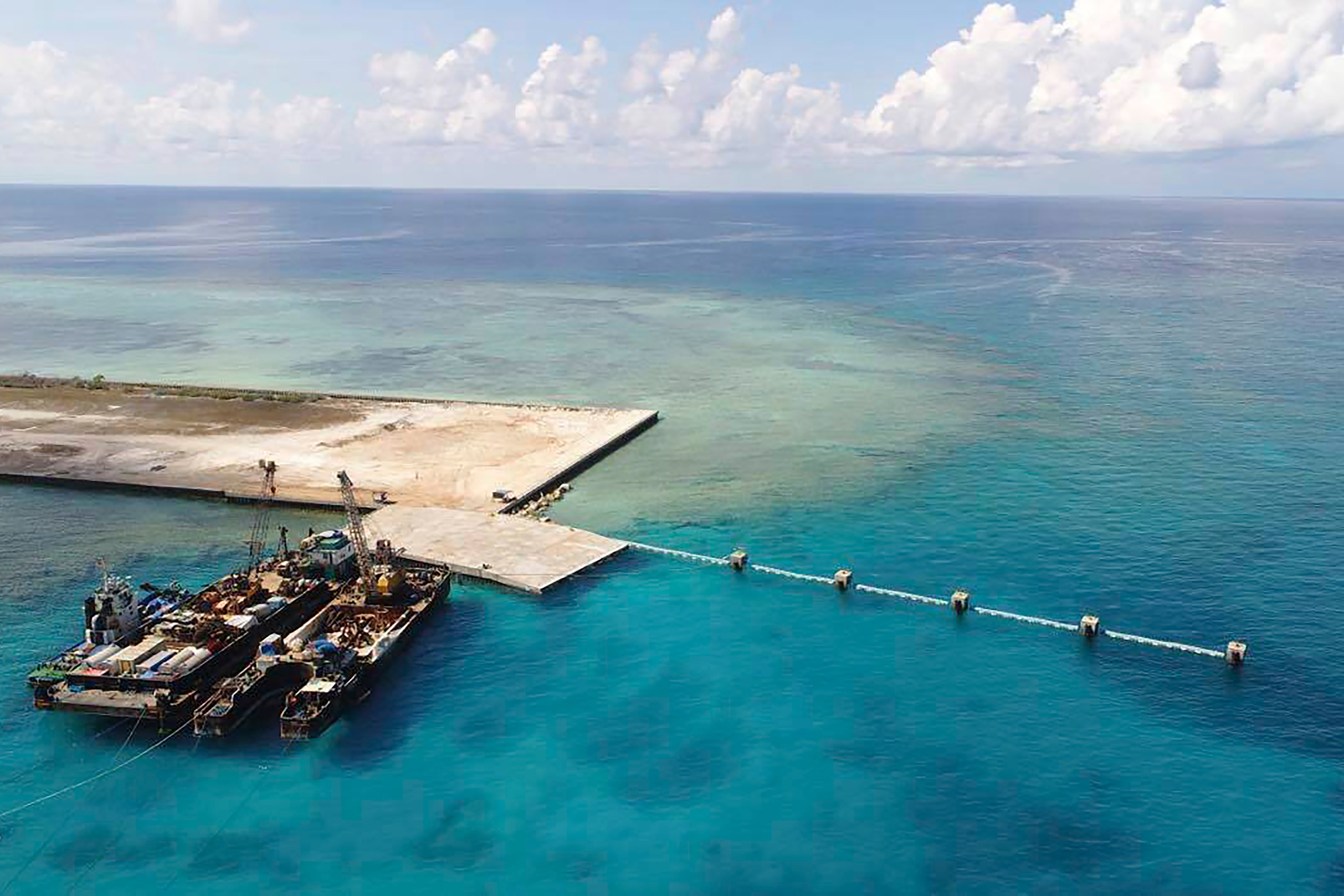 <p>In this photo from 9 June 2020, provided by the Department of National Defense, ships carrying construction materials are docked at the newly built beach ramp at the Philippine-claimed island of Thitu, in the disputed South China Sea</p>
