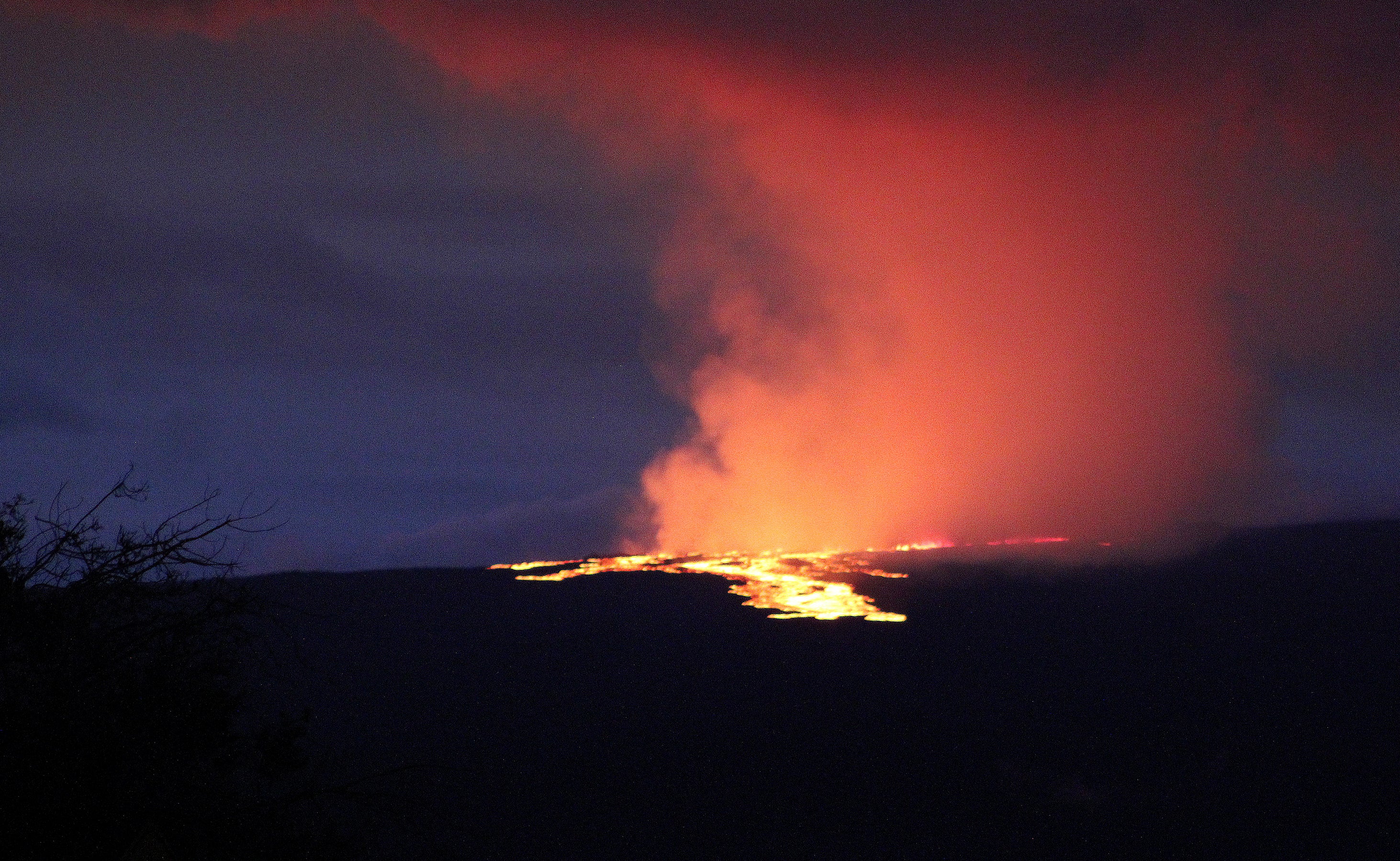 Lava pours out of the summit crater of Mauna Loa about 6:35am on 28 November 28 2022, as seen from Gilbert Kahele Recreation Area on Maunakea, Hawaii