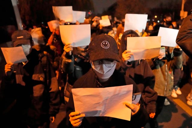 <p>Protesters hold up blank papers and chant slogans as they march in Beijing</p>