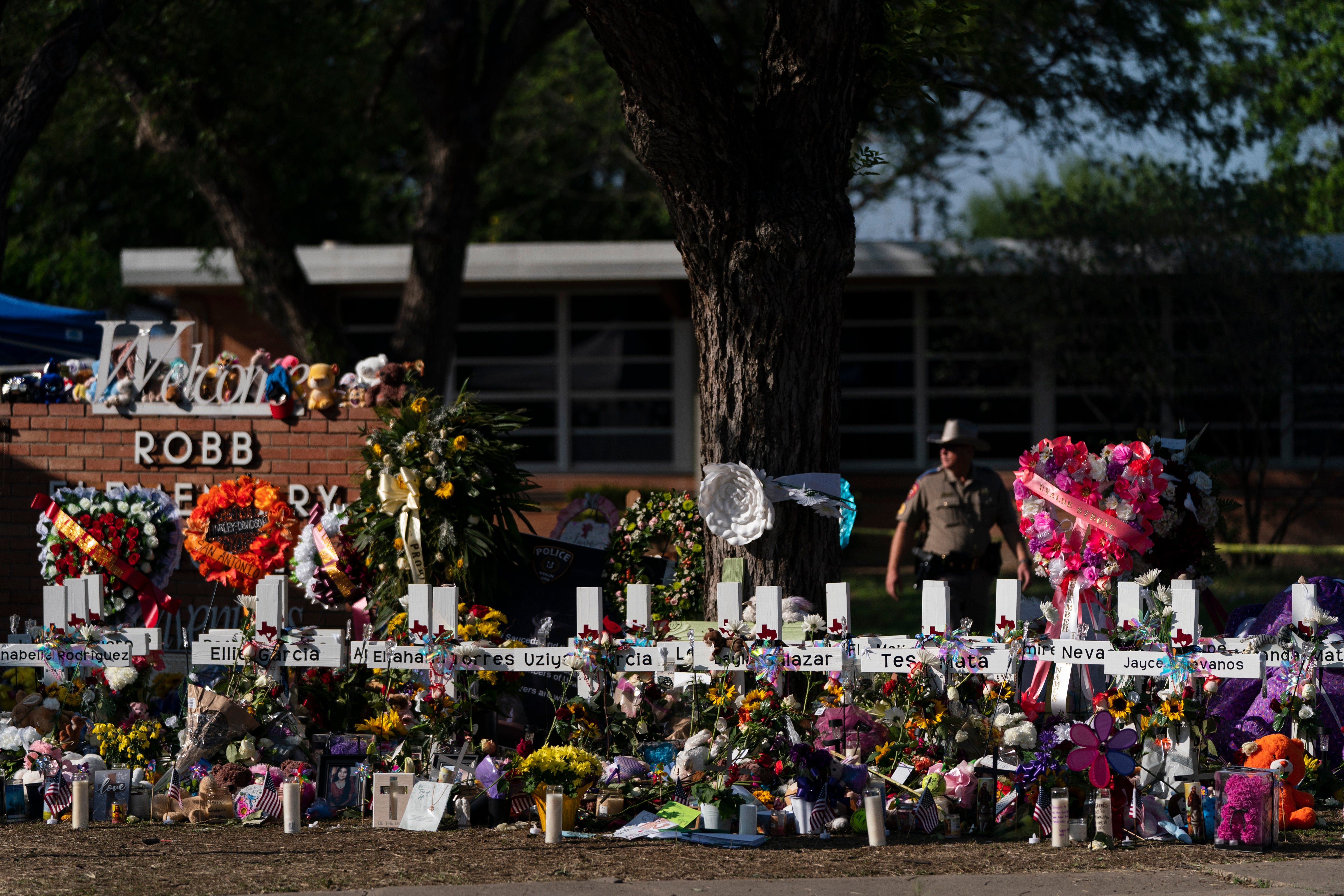 Flowers and candles are placed around crosses at a memorial outside Robb Elementary School in Uvalde, Texas, to honor the victims killed in the shooting