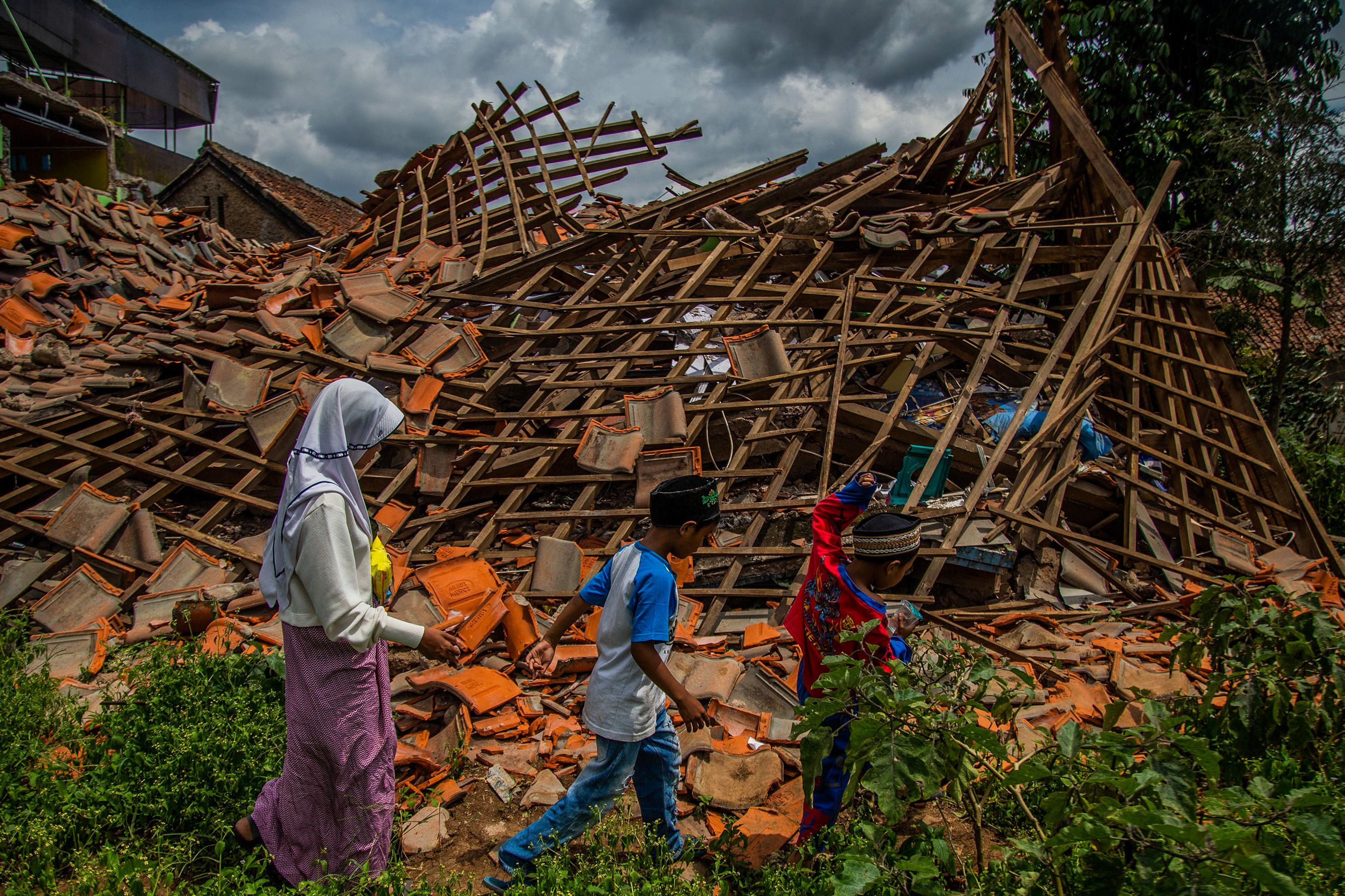 Children of earthquake victims walk past a collapsed house at Cugenang village in Cianjur, West Java