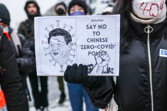 <p>A demonstrator holds a banner with an image of Chinese president Xi Jinping, during a protest in front of the Chinese embassy in Berlin in solidarity with protesters in China</p>