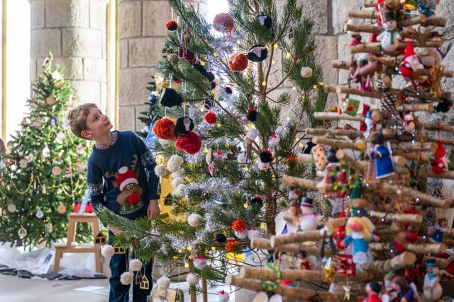 Robert Hodge, eight, views some of the 63 trees during the annual Christmas tree festival, at Saint Conan’s Kirk, Lochawe in Argyll (PA)