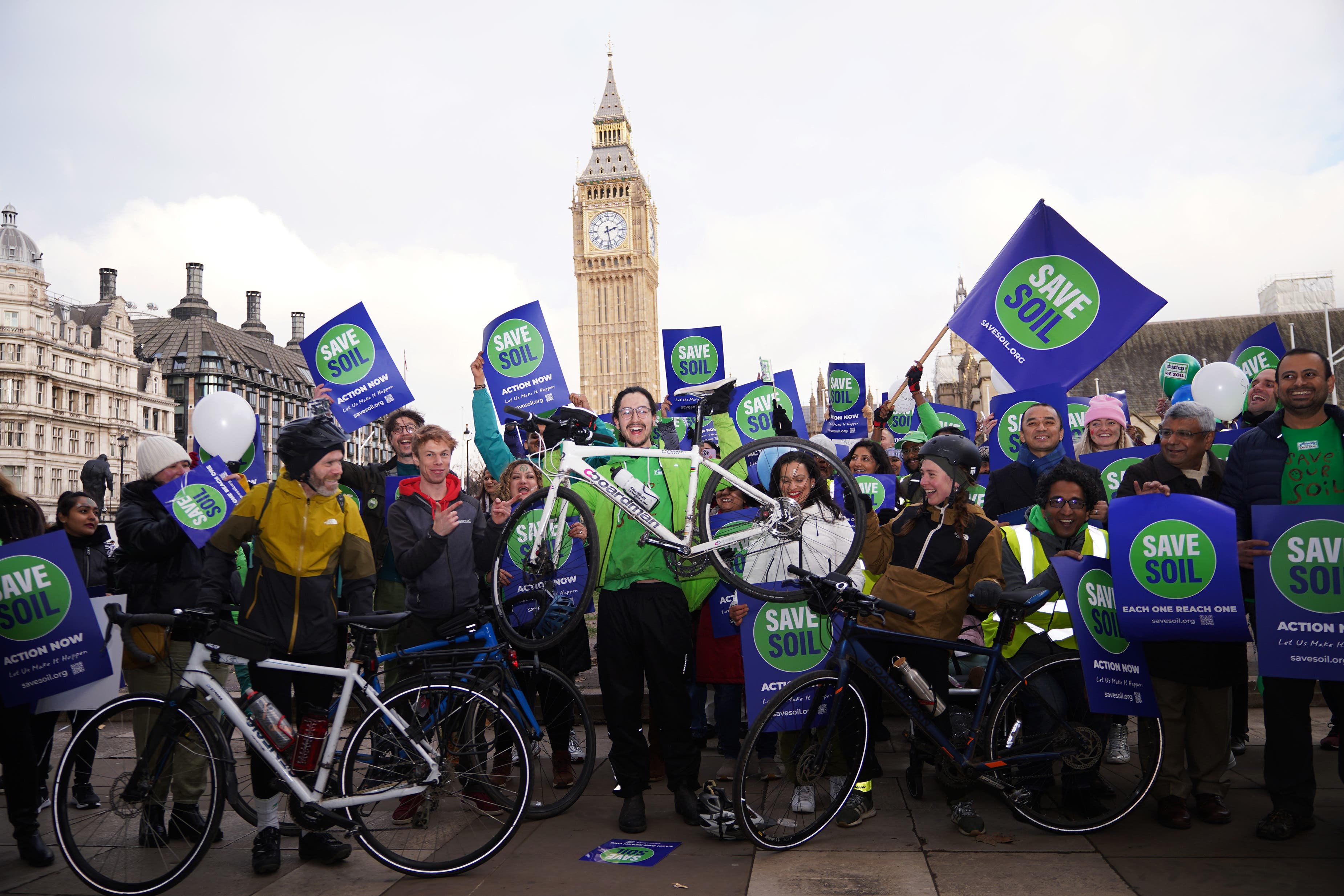 <p>Oscar Smith (centre, holding bike), 17, was welcomed by a group of Save Soil supporters in Parliament Square </p>